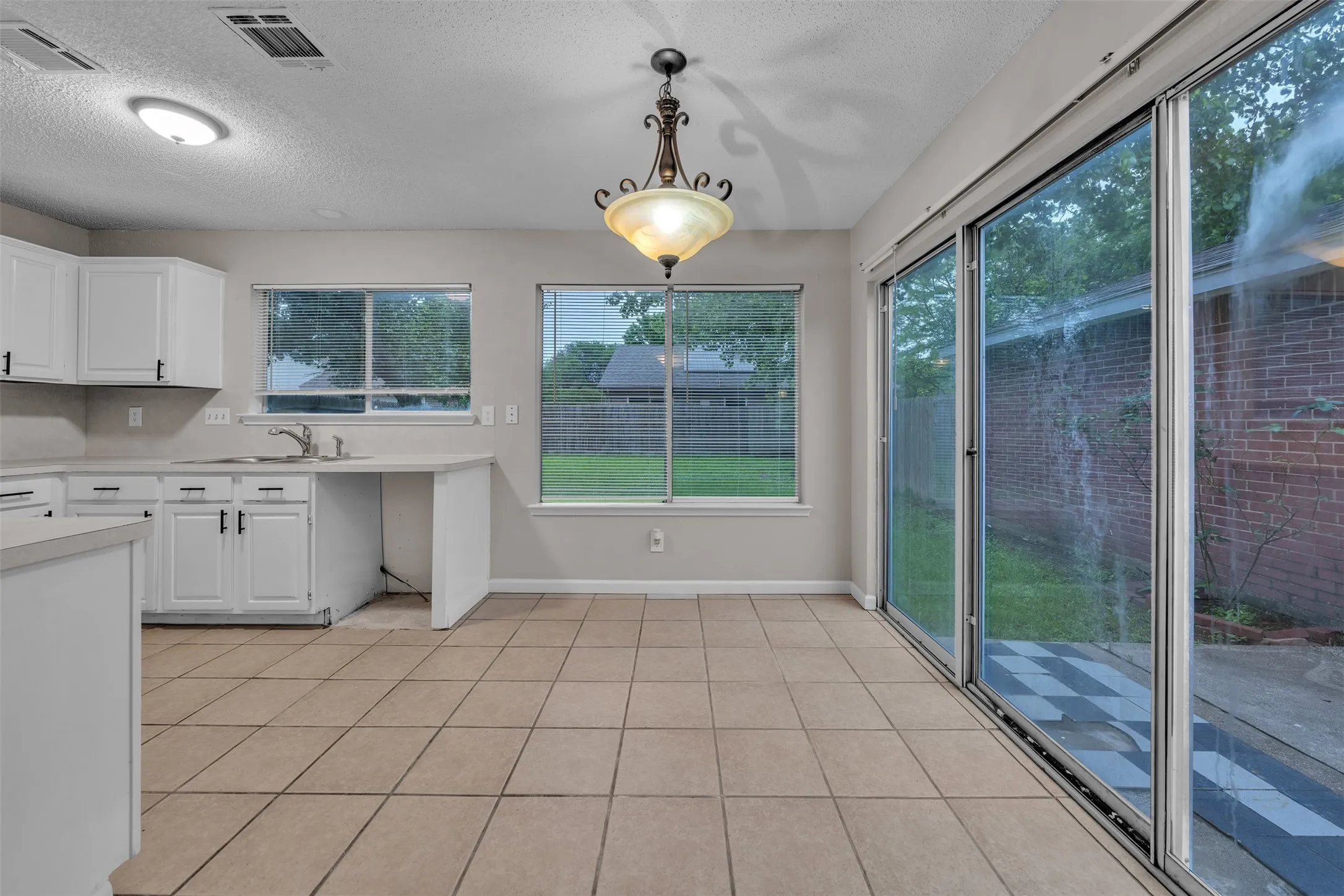 Kitchen dining area featuring neutral tile flooring and a decorative chandelier