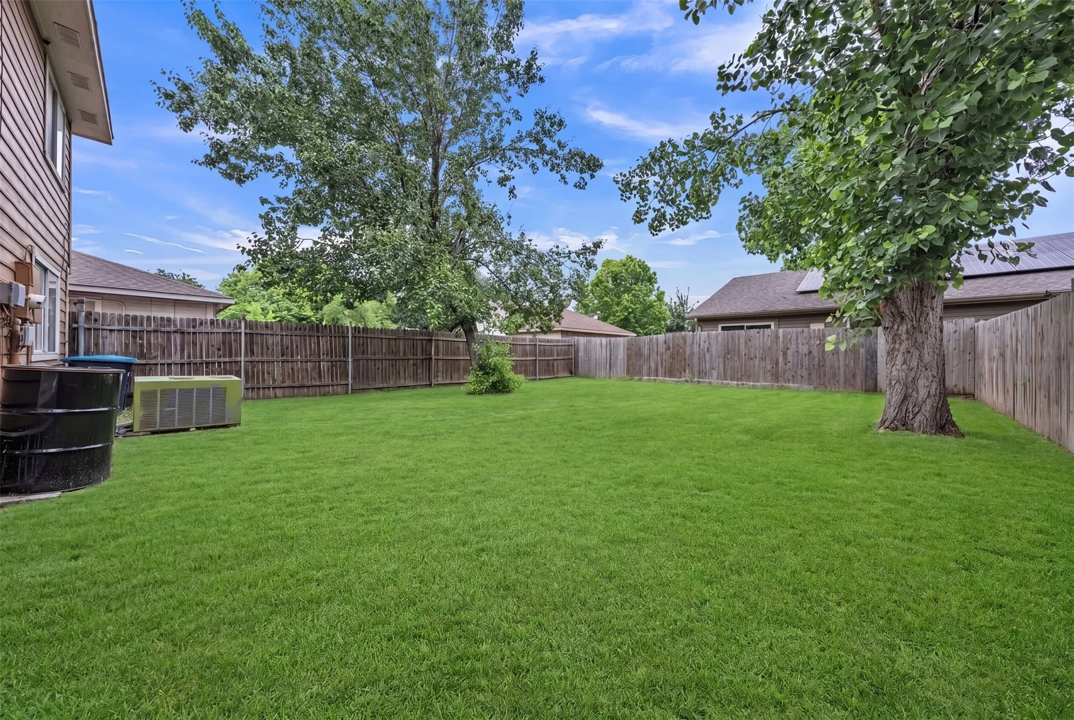 Expansive green lawn enclosed by a wood privacy fence