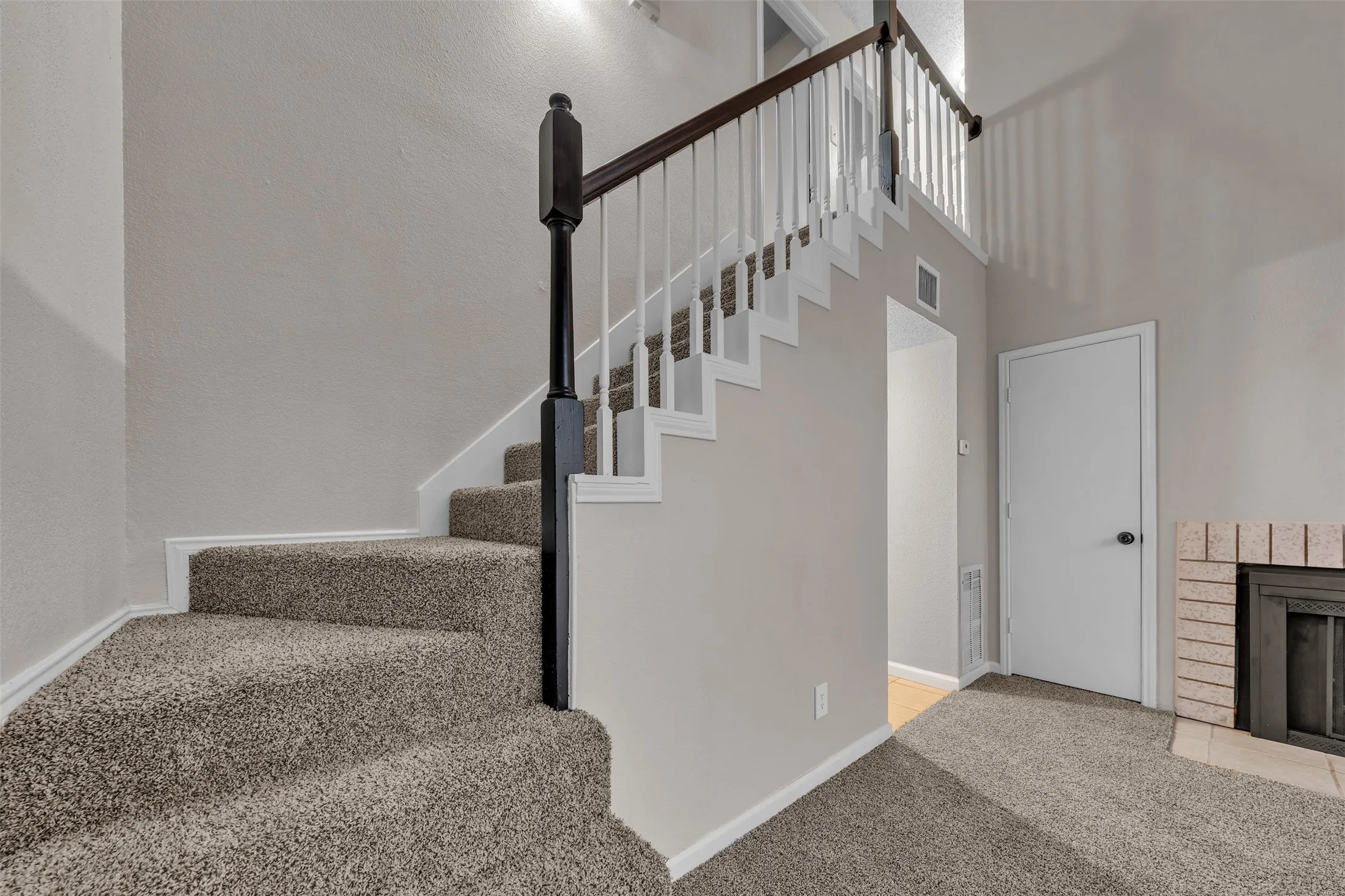 Carpeted staircase with dark wood newel post and railing