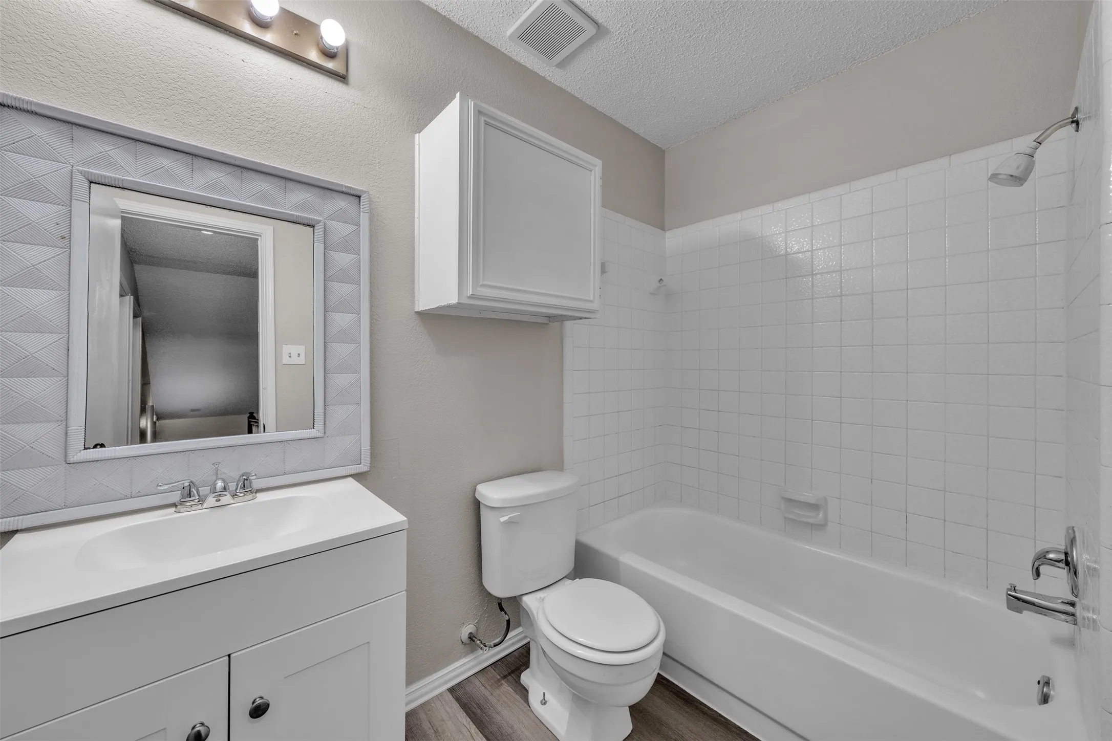 Bathroom featuring a white vanity with integrated sink, chrome faucet, and decorative framed mirror