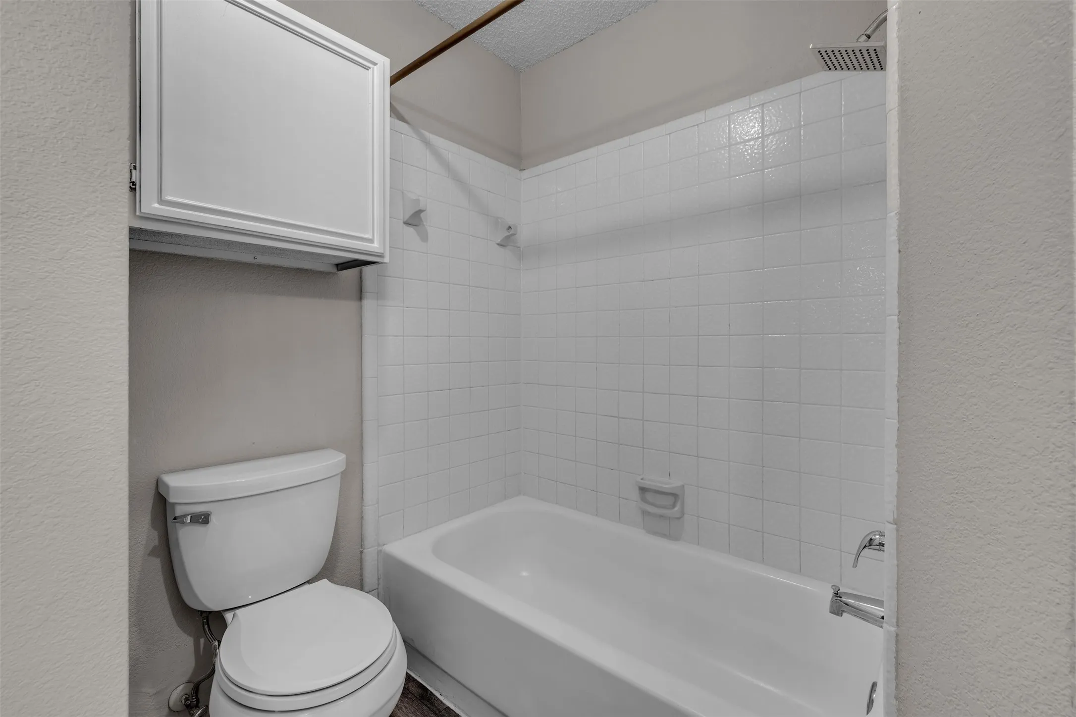 Bathroom featuring a white subway tile tub surround, integrated bathtub, and a modern square showerhead