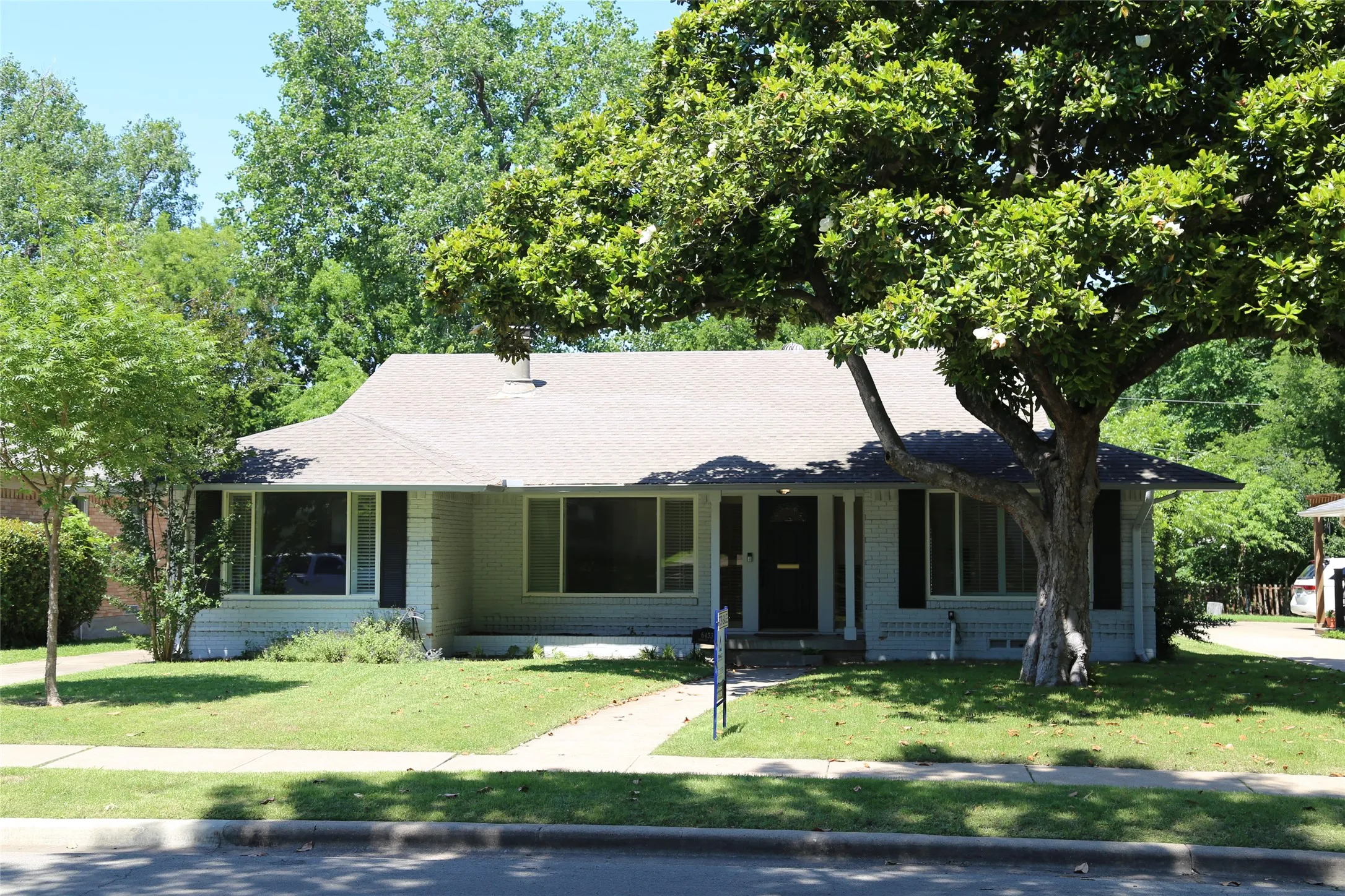 Ranch-style residence featuring a prominent front yard with a mature tree