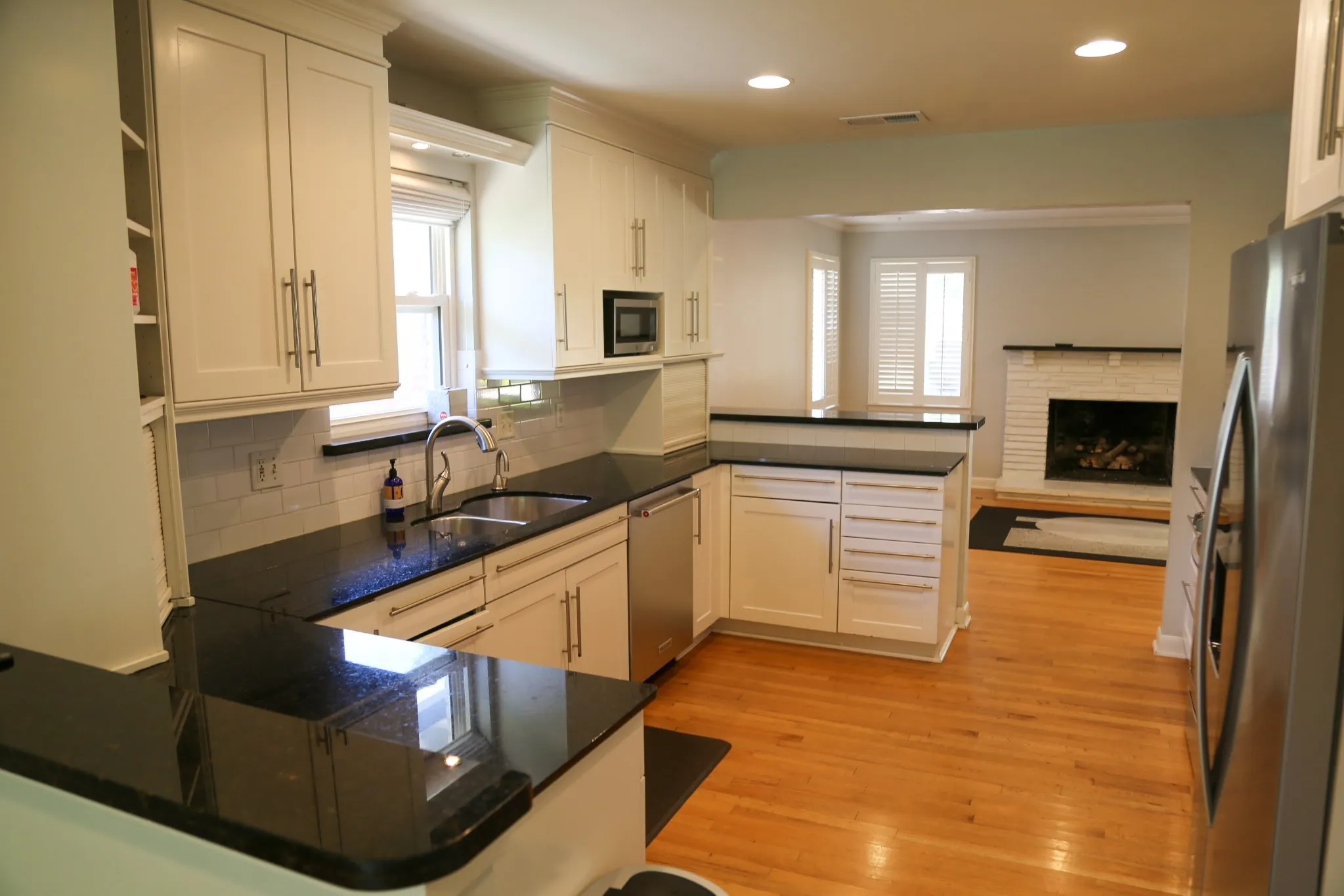 Kitchen featuring wood-finish flooring, white cabinetry, black countertops, and stainless steel appliances