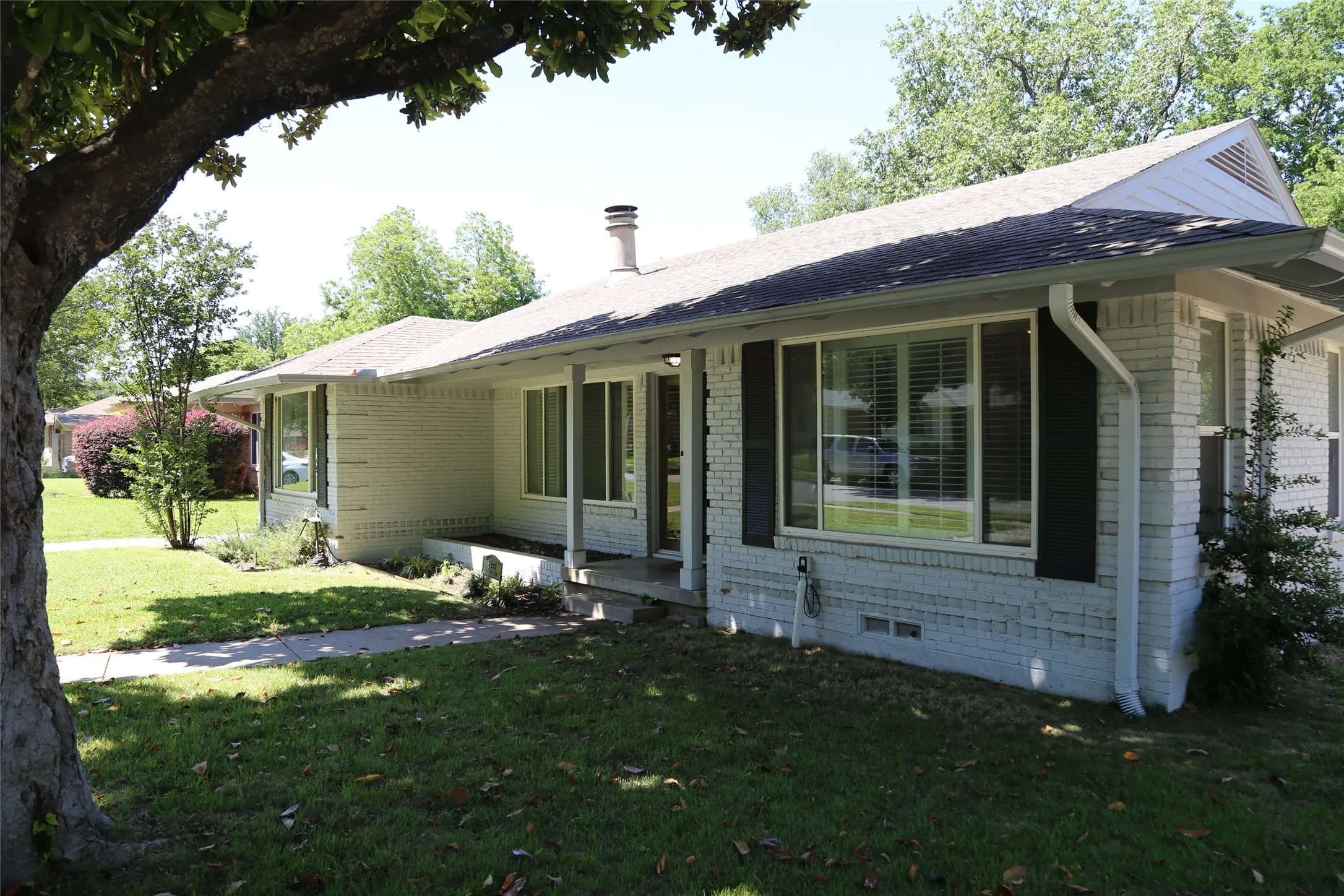 Painted brick exterior featuring black louvered shutters and white trim