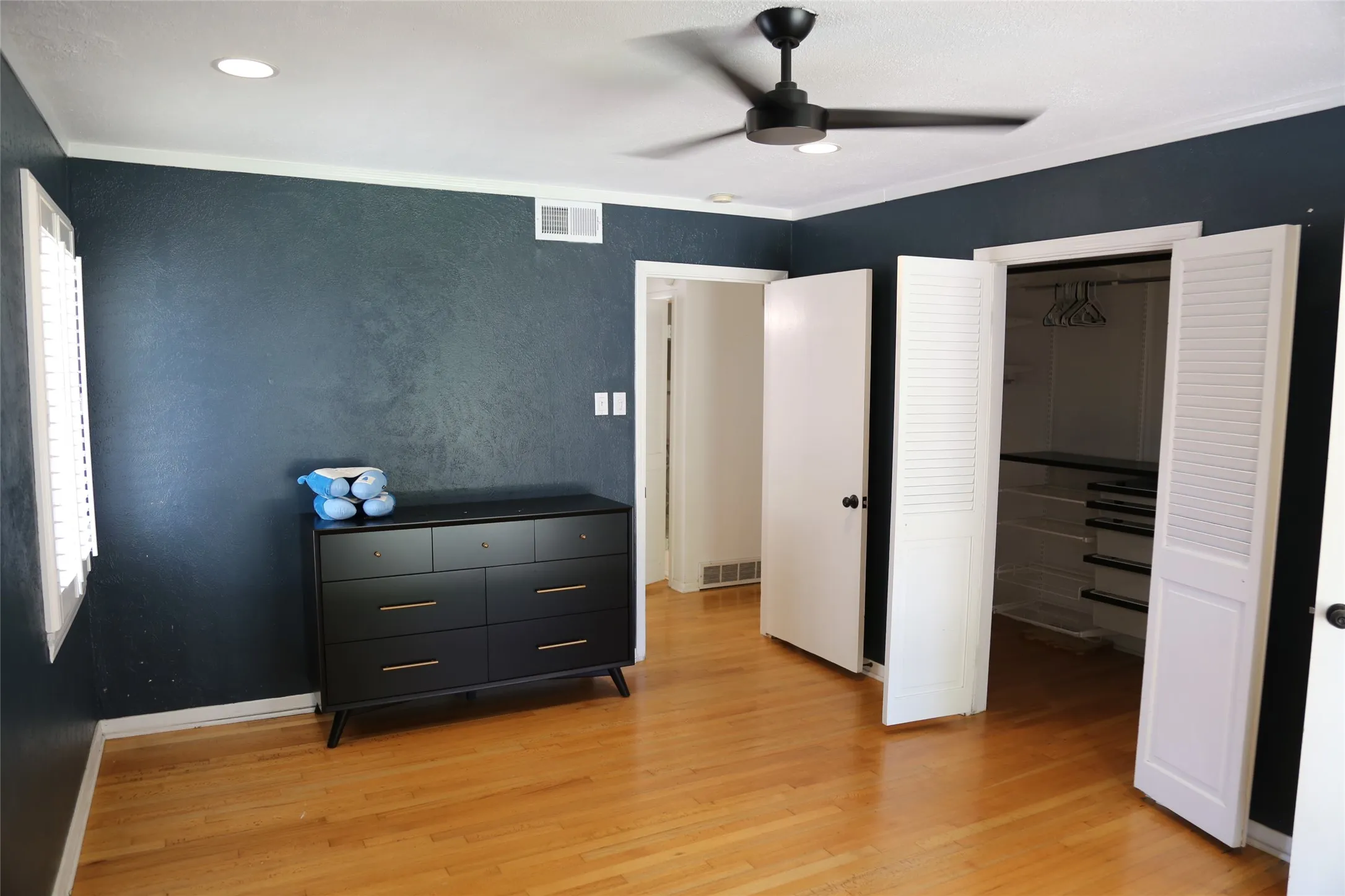Hardwood flooring throughout featuring a modern ceiling fan with integrated lighting, recessed ceiling lighting, and plantation shutters