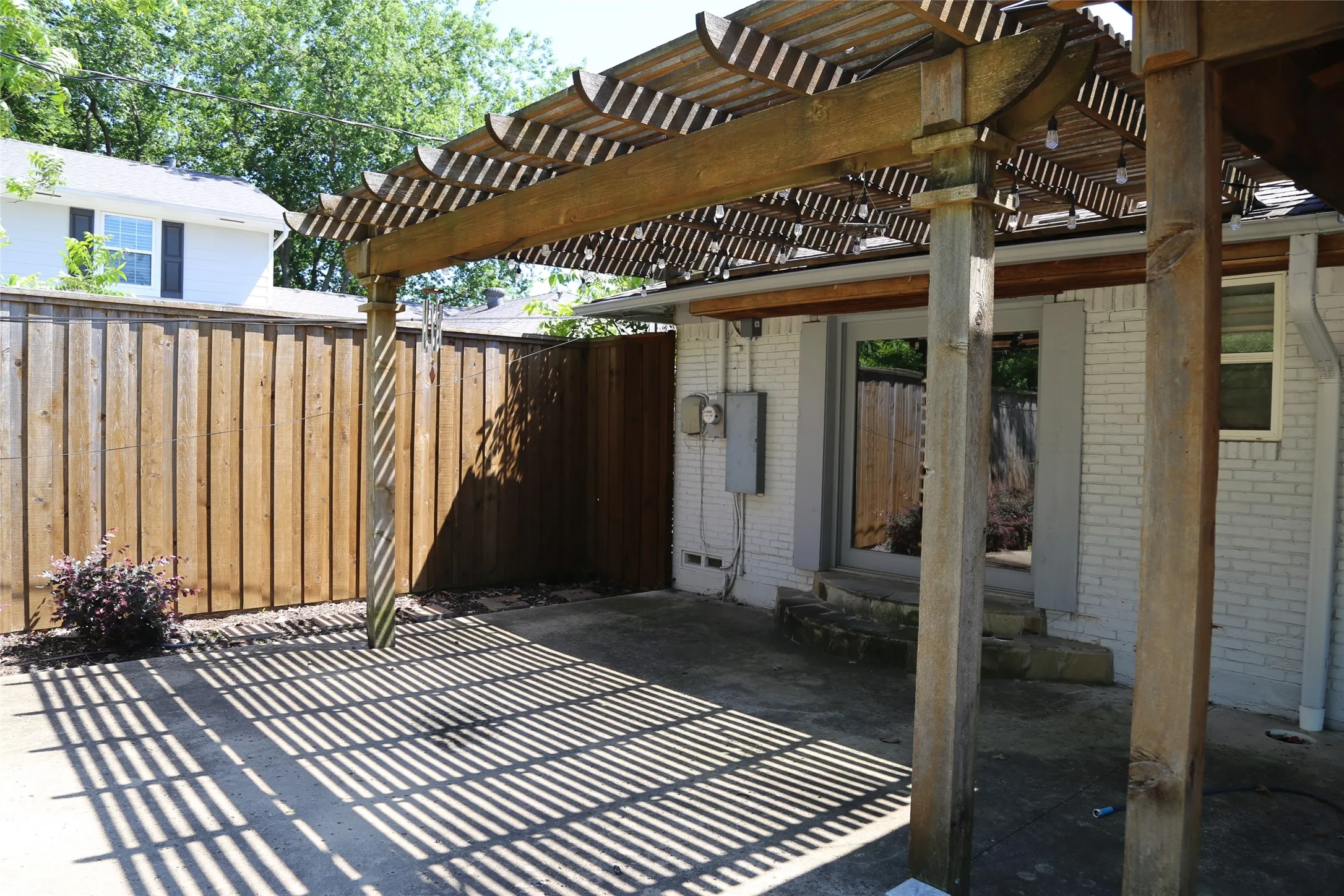 Outdoor patio featuring a slatted wood pergola, providing dappled shade