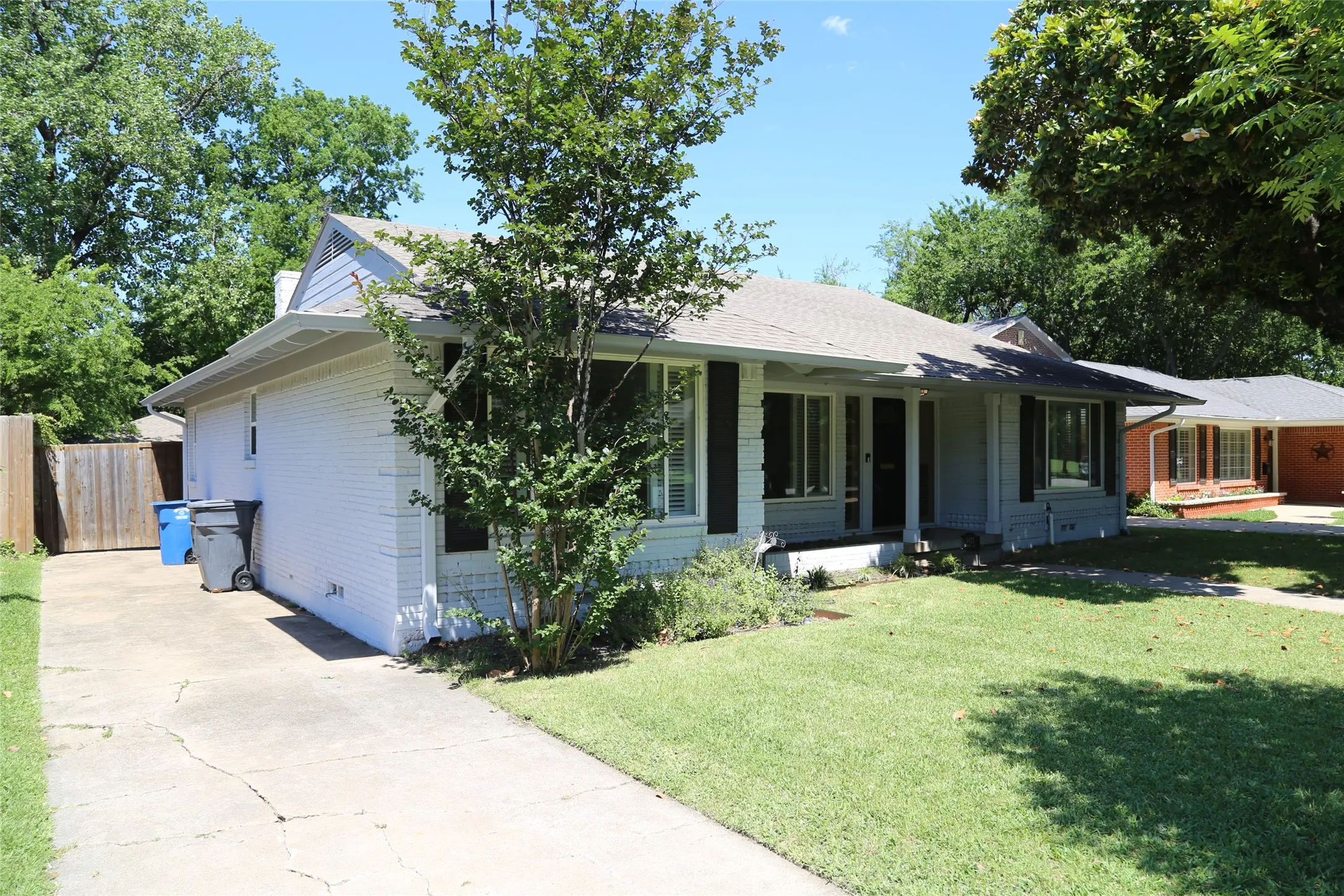 White brick exterior with a gray roof and dark shutters