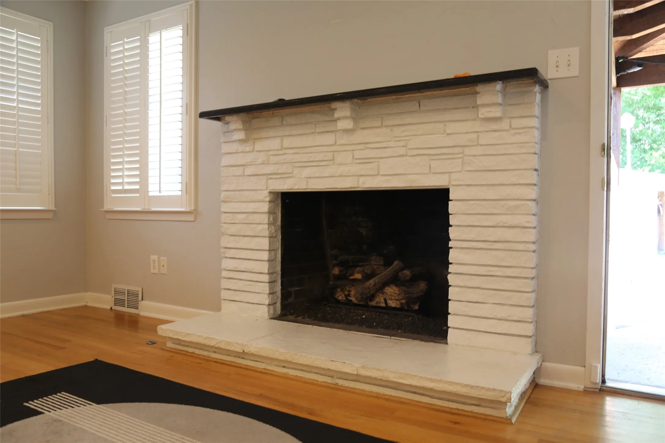 Stone-faced fireplace with a dark wood-finish mantel and a matching hearth
