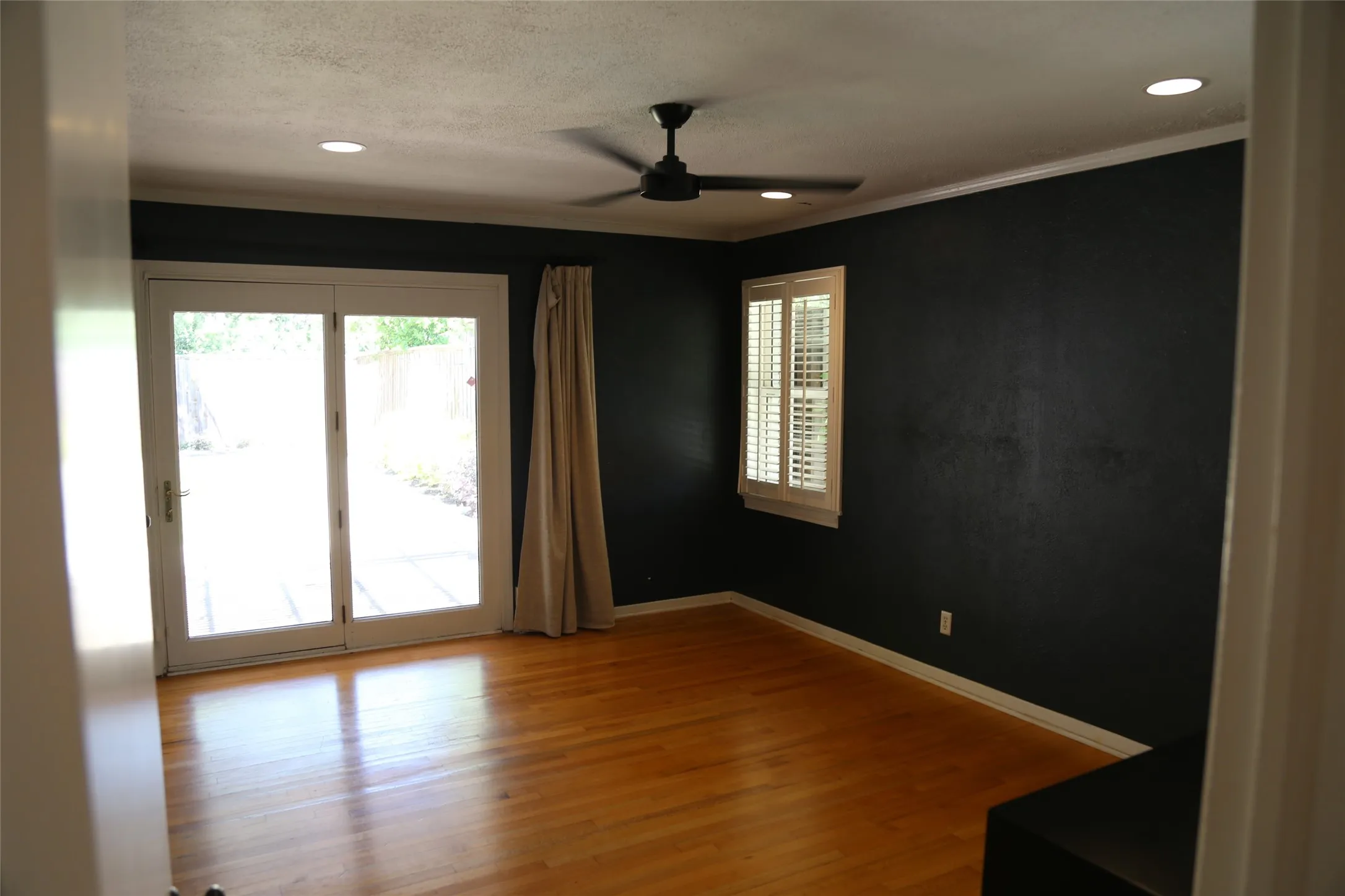 Hardwood flooring features a dark accent wall, recessed lighting, and a ceiling fan