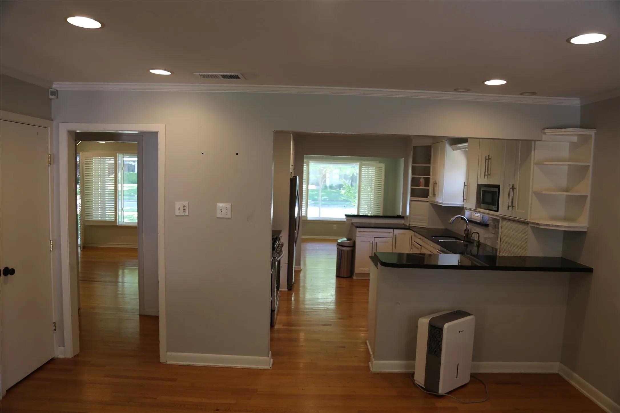 Kitchen featuring white cabinetry, dark countertops, a double basin sink, and recessed lighting