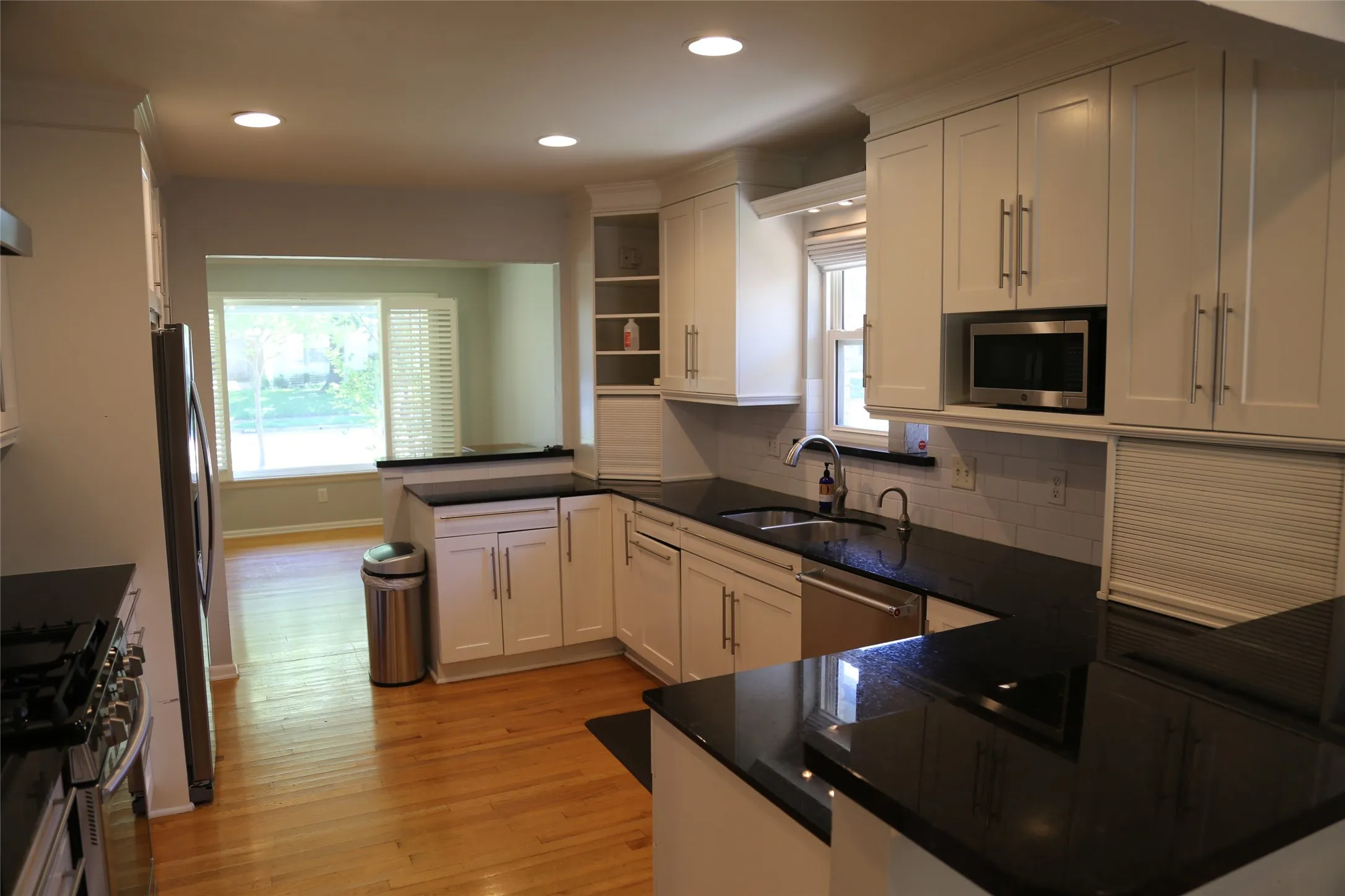 Kitchen with white shaker cabinetry, stainless steel appliances, dark countertops, and a subway tile backsplash