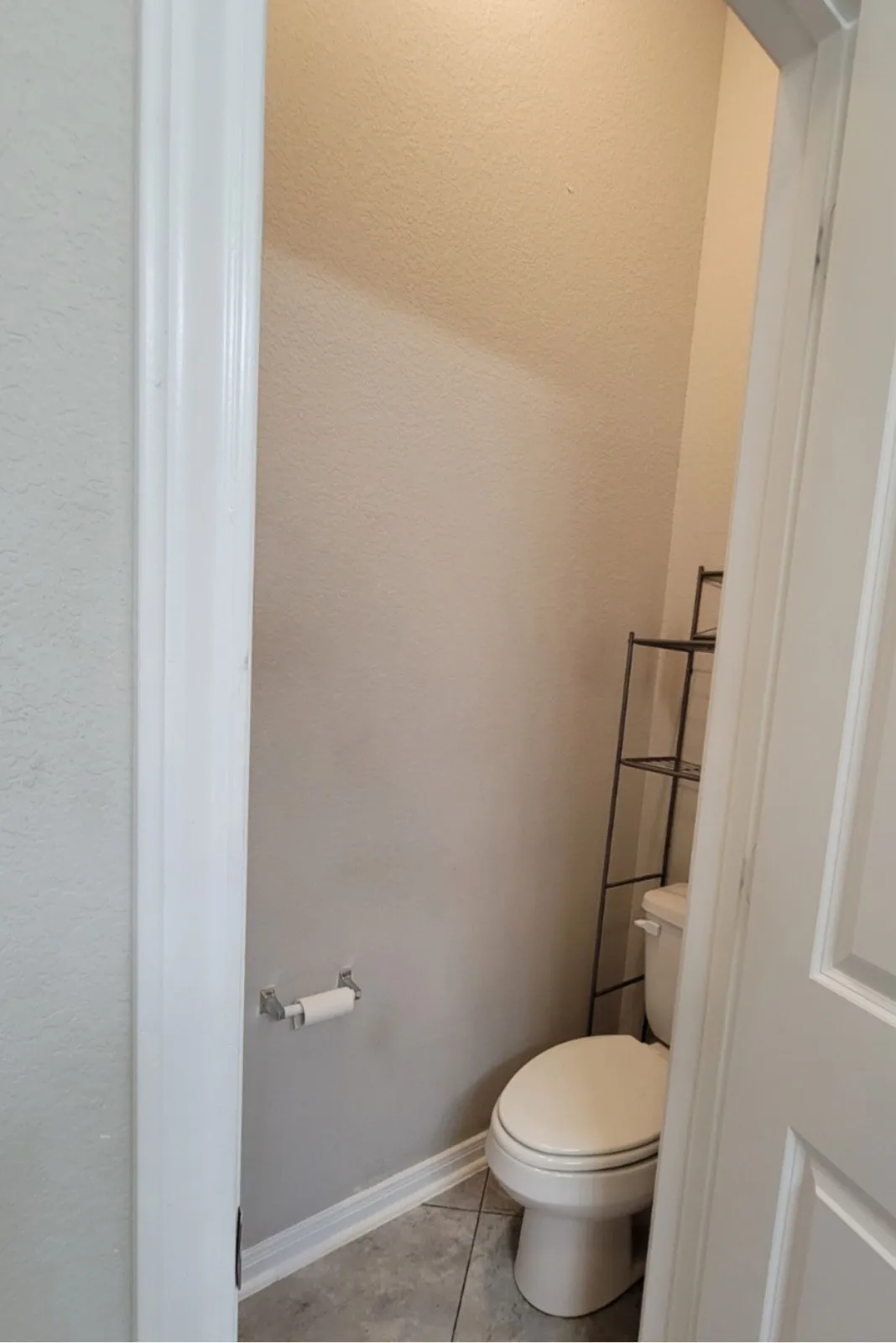 Powder room featuring a standard toilet, tiled flooring, and a wall-mounted toilet paper holder