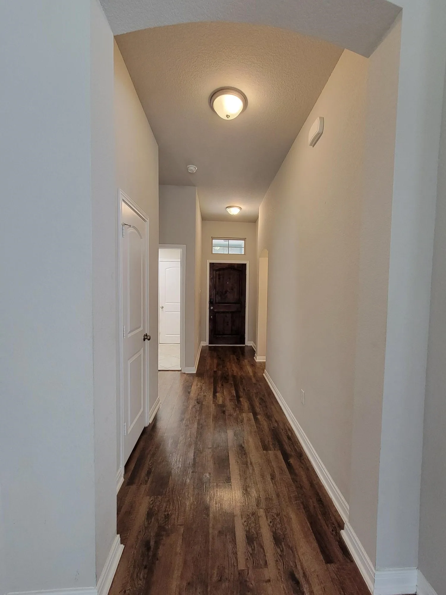 Entry corridor featuring wood-finish flooring, white baseboards, and neutral wall tones