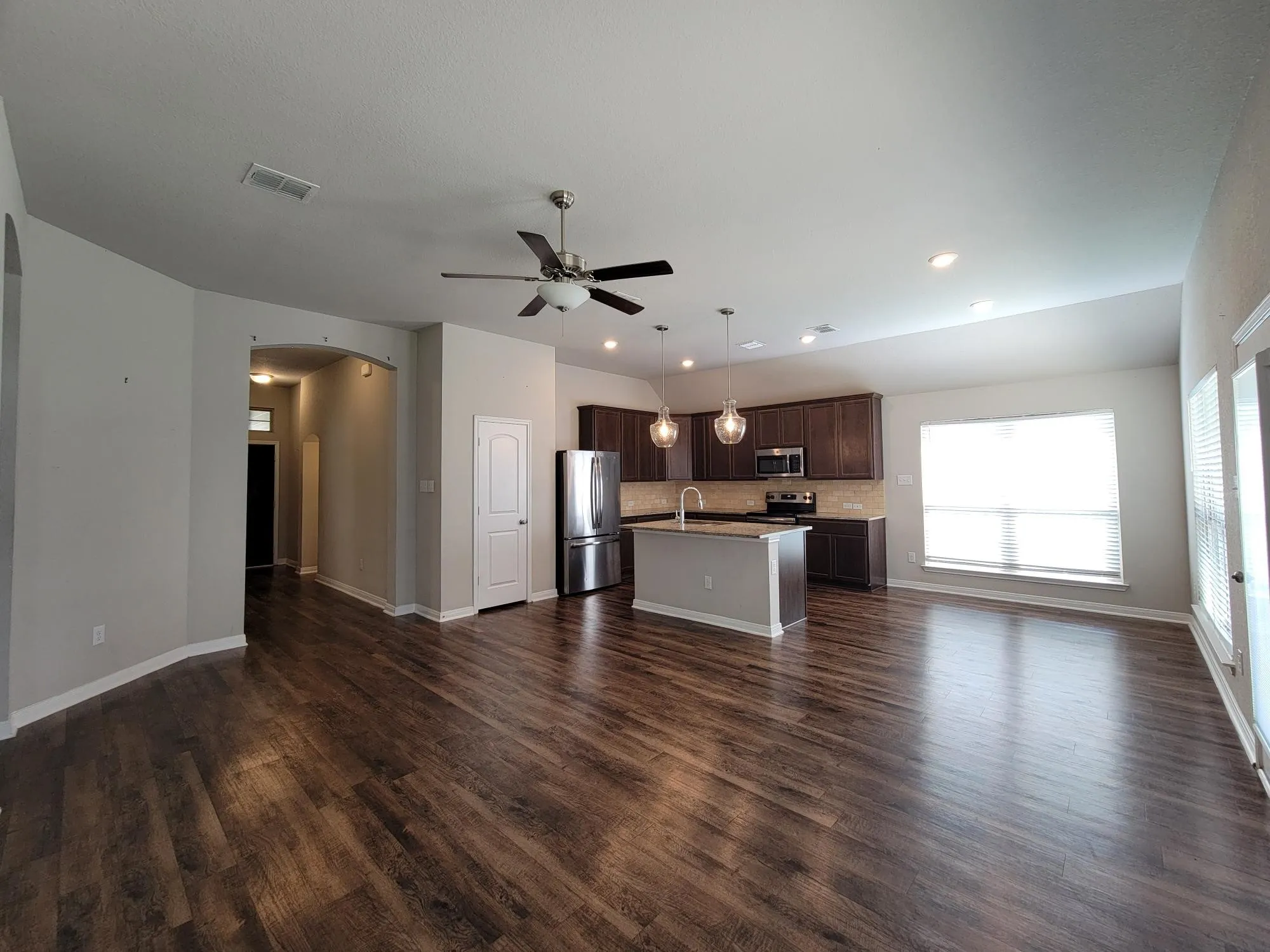 Spacious living area featuring wood-finish flooring, recessed lighting, and a ceiling fan