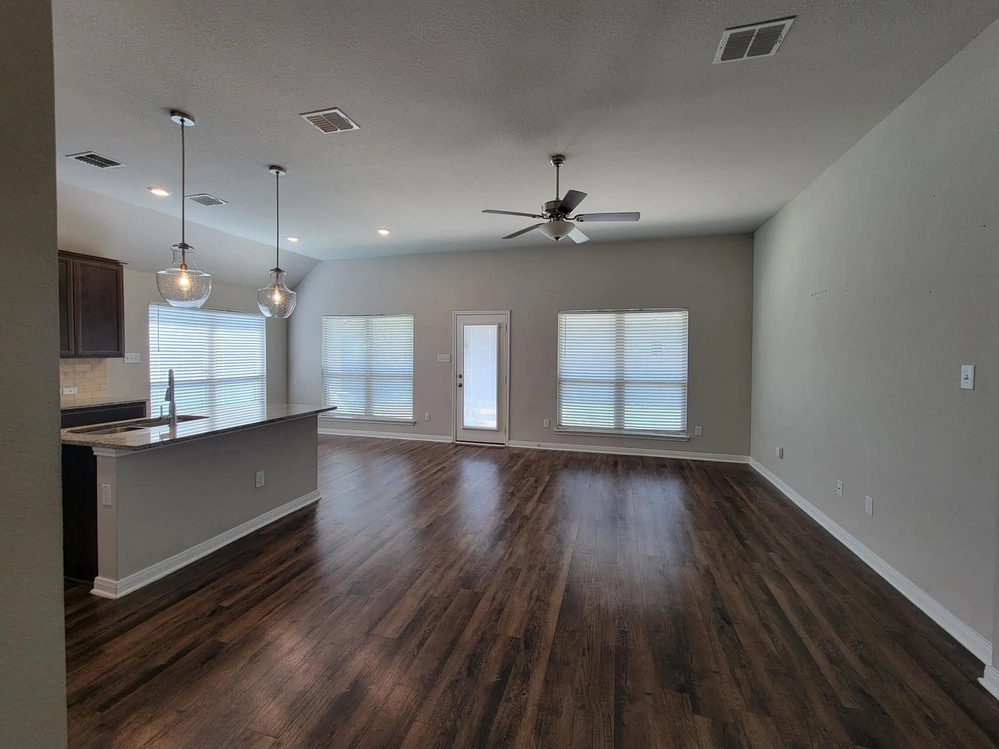 Open-concept living space featuring wood-finish flooring, recessed lighting, and a ceiling fan