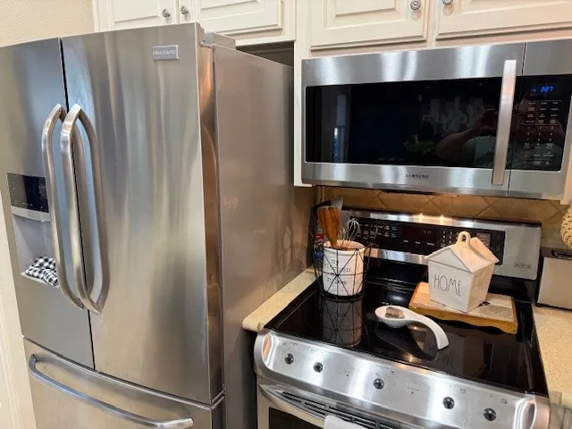 Stainless steel refrigerator, microwave, and range with a black ceramic cooktop