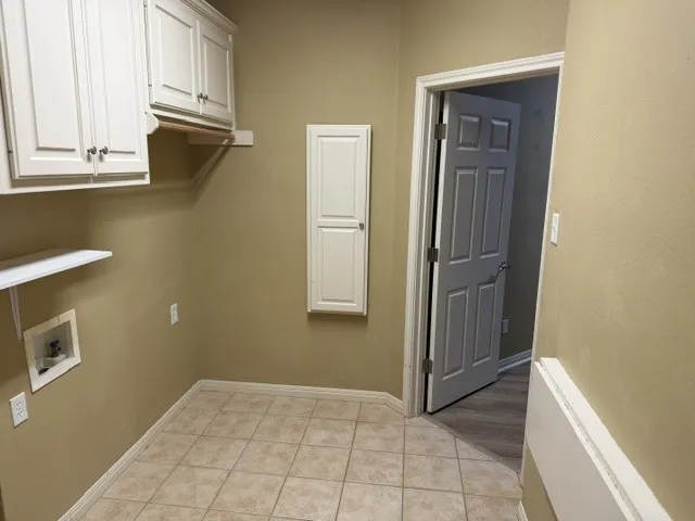 Tile flooring, upper cabinetry, wall-mounted shelving, and a paneled interior door