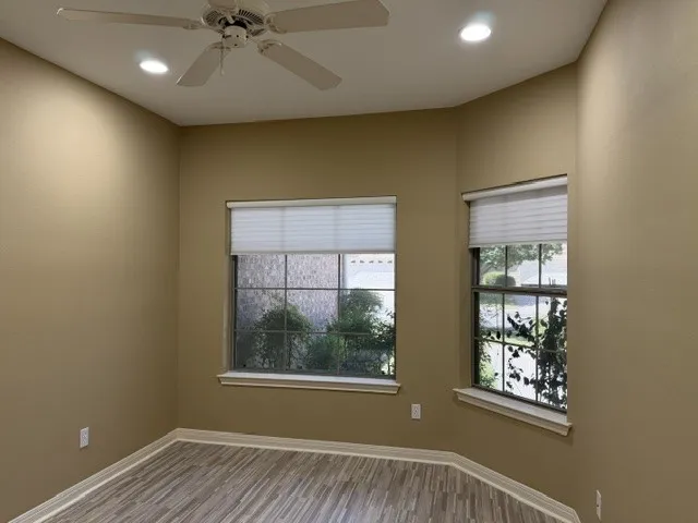 Bay window with natural light, wood-finish flooring, ceiling fan, and recessed lighting