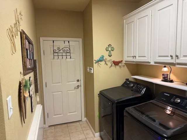 Utility room featuring a paneled door, tile flooring, and upper cabinetry with crown molding