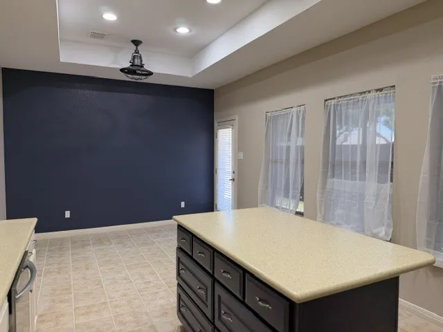Kitchen island with a light-toned countertop and dark wood-finish cabinetry