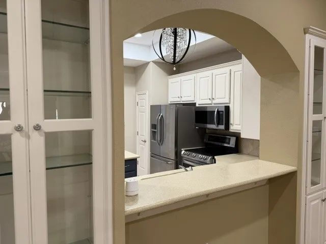 Kitchen with white cabinetry, stainless steel appliances, a breakfast bar, and a decorative archway