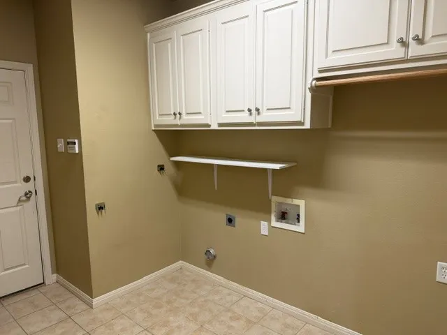 Built-in upper cabinetry, wood-finish hanging rod, wall-mounted shelf, and tile flooring
