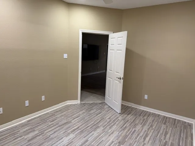 Wood-finish flooring with a linear pattern, neutral painted walls, and white trim
