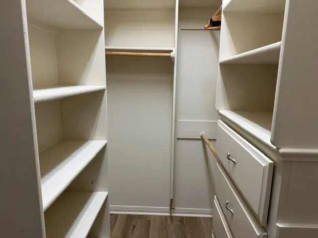 Built-in closet system with shelving, hanging rods, and pull-out drawers featuring chrome hardware