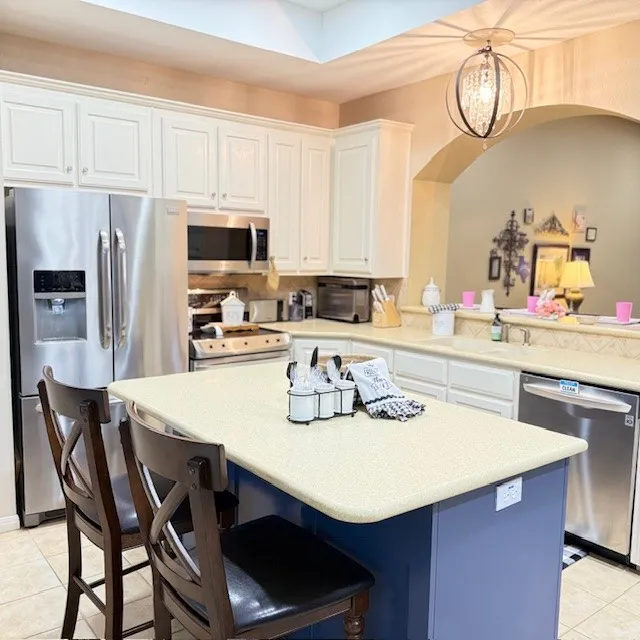 Kitchen featuring an island with a blue base, light-toned countertop, and recessed lighting