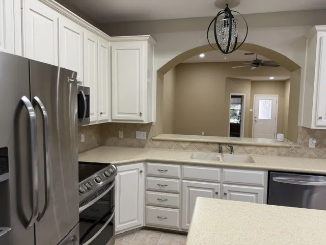 Kitchen featuring light-toned cabinetry, stainless steel appliances, a double basin sink, and an arched pass-through window