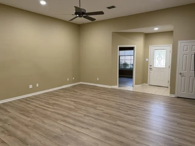 Spacious room featuring wood-finish flooring, recessed lighting, and a ceiling fan