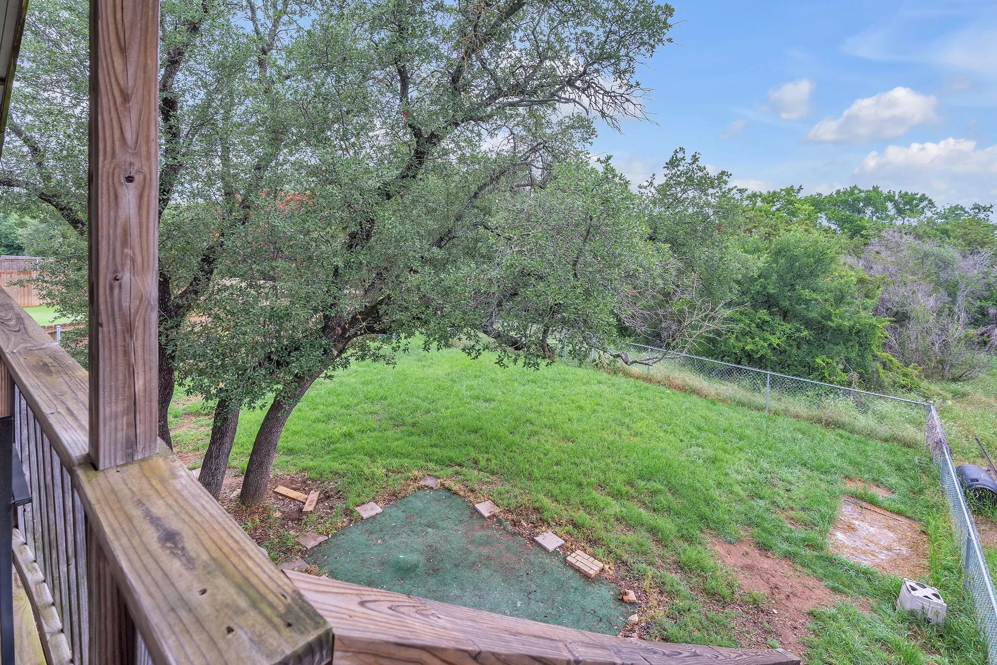 Another backyard perspective featuring mature trees and a peaceful setting. Great balance of shade and open space.