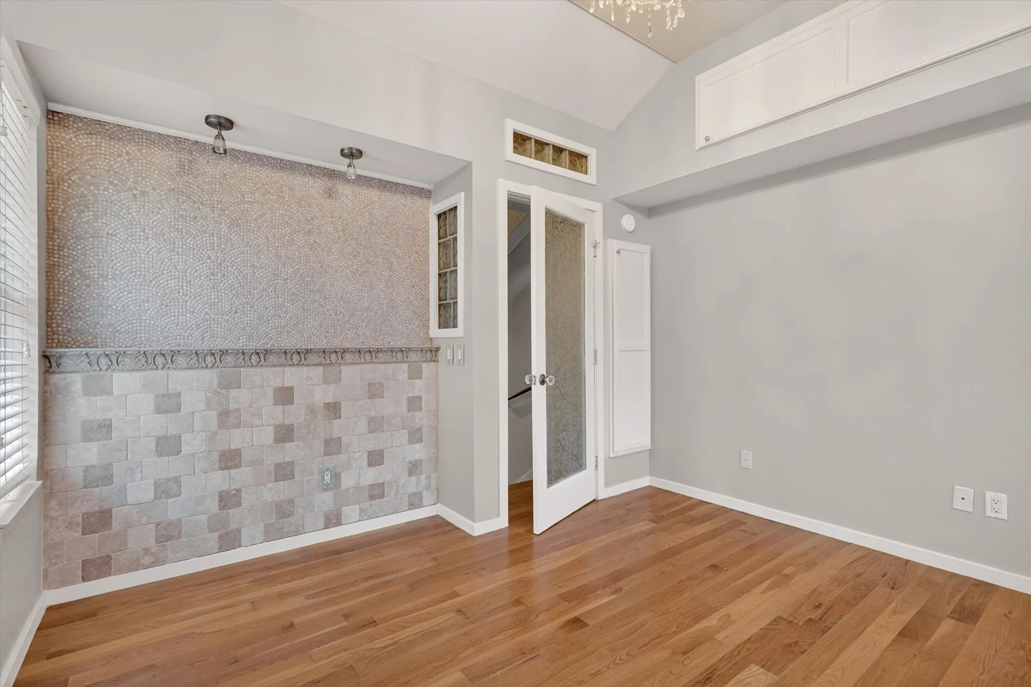 Interior space featuring wood-finish flooring, light gray wall paint, and a vaulted ceiling