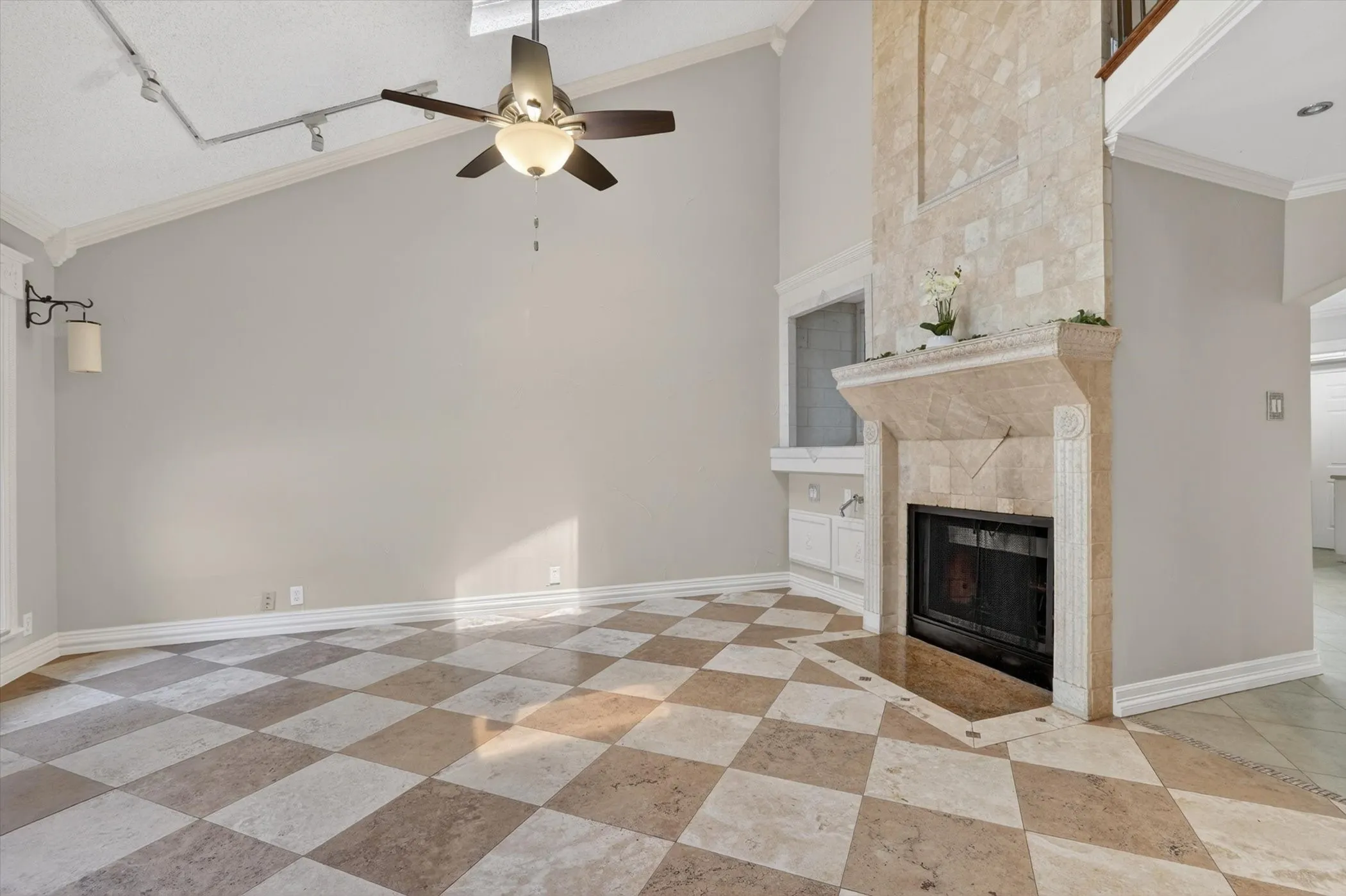 Living area featuring a floor-to-ceiling stone fireplace, checkerboard-patterned tile flooring, vaulted ceilings, a ceiling fan, and track lighting