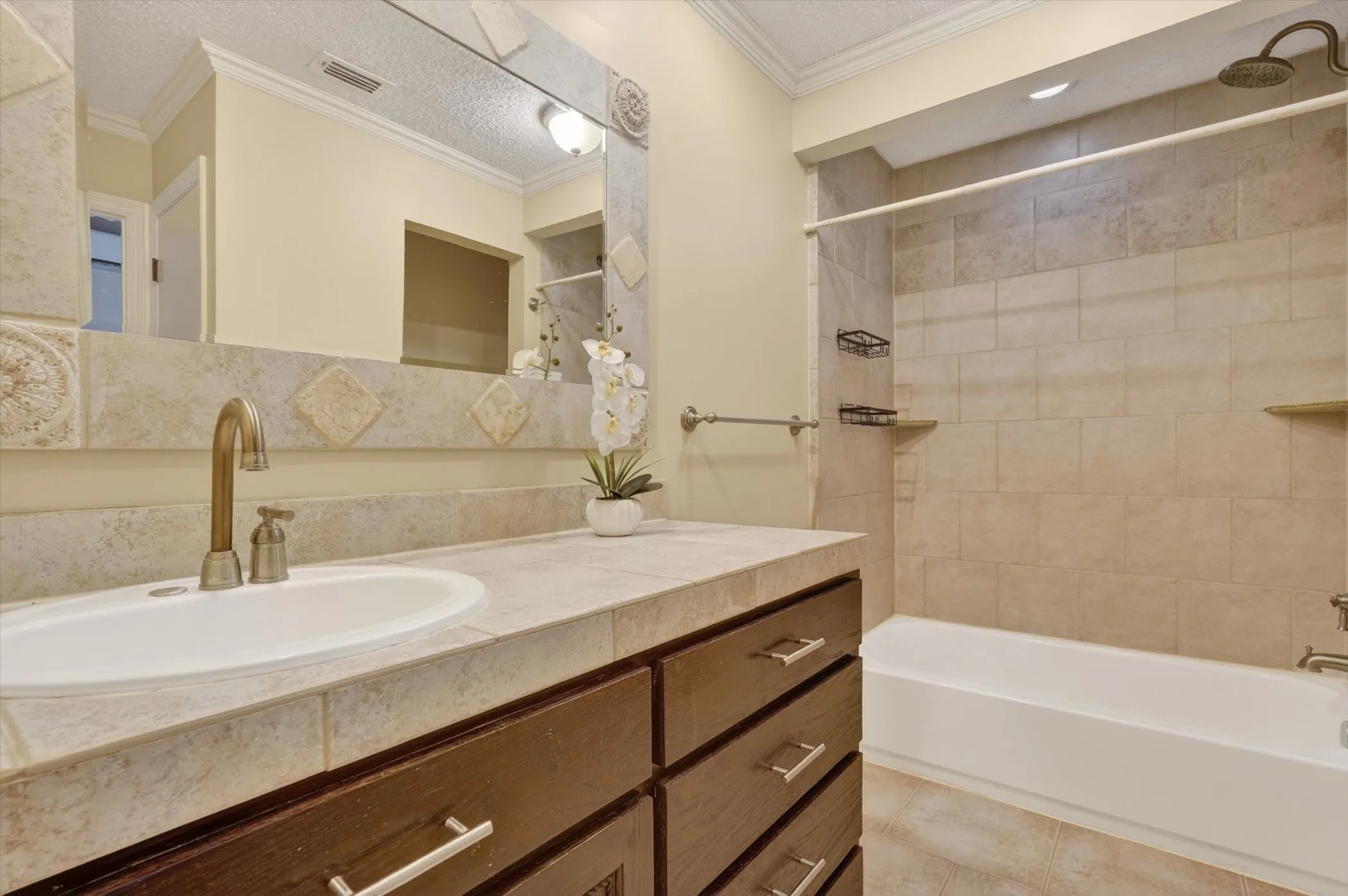 Bathroom featuring a vanity with an integrated sink, tile countertop, and dark wood-finish cabinetry with brushed nickel hardware