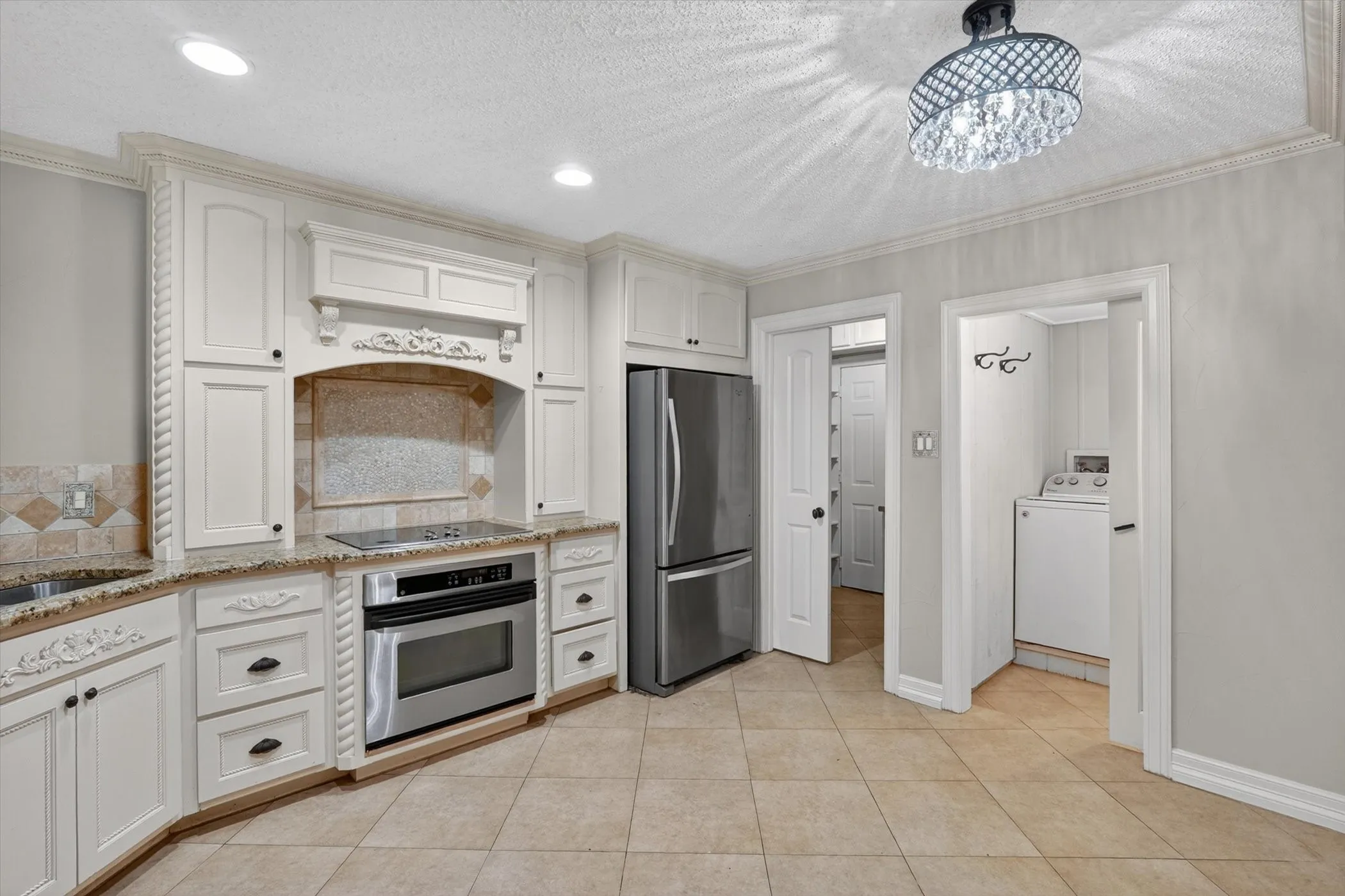Kitchen featuring light cabinetry with ornate detailing, granite-finish countertops, and a built-in stainless steel oven