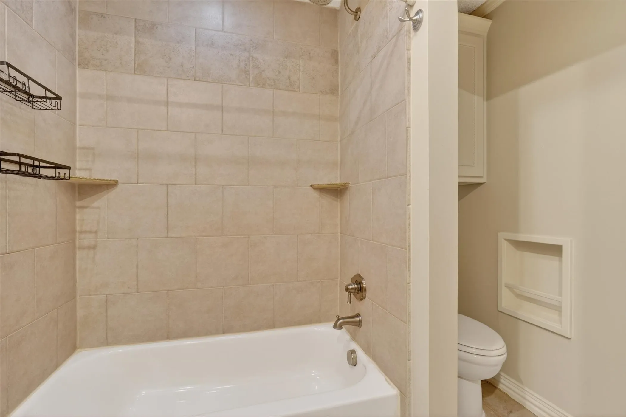 Bathroom featuring a bathtub with tile surround, built-in wall niche, and an overhead shower fixture