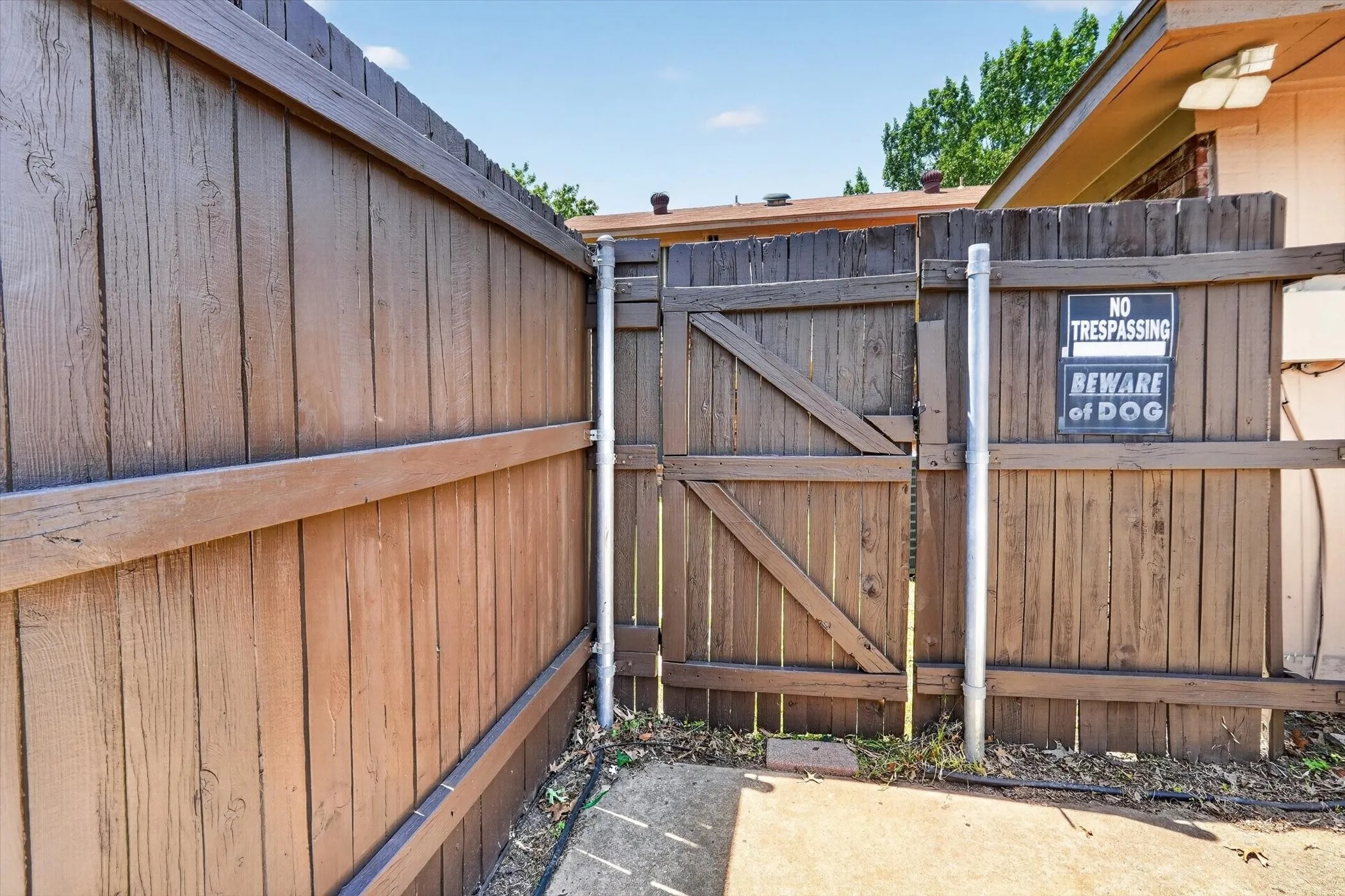 Wood-plank fencing with a secure gate and solid concrete ground