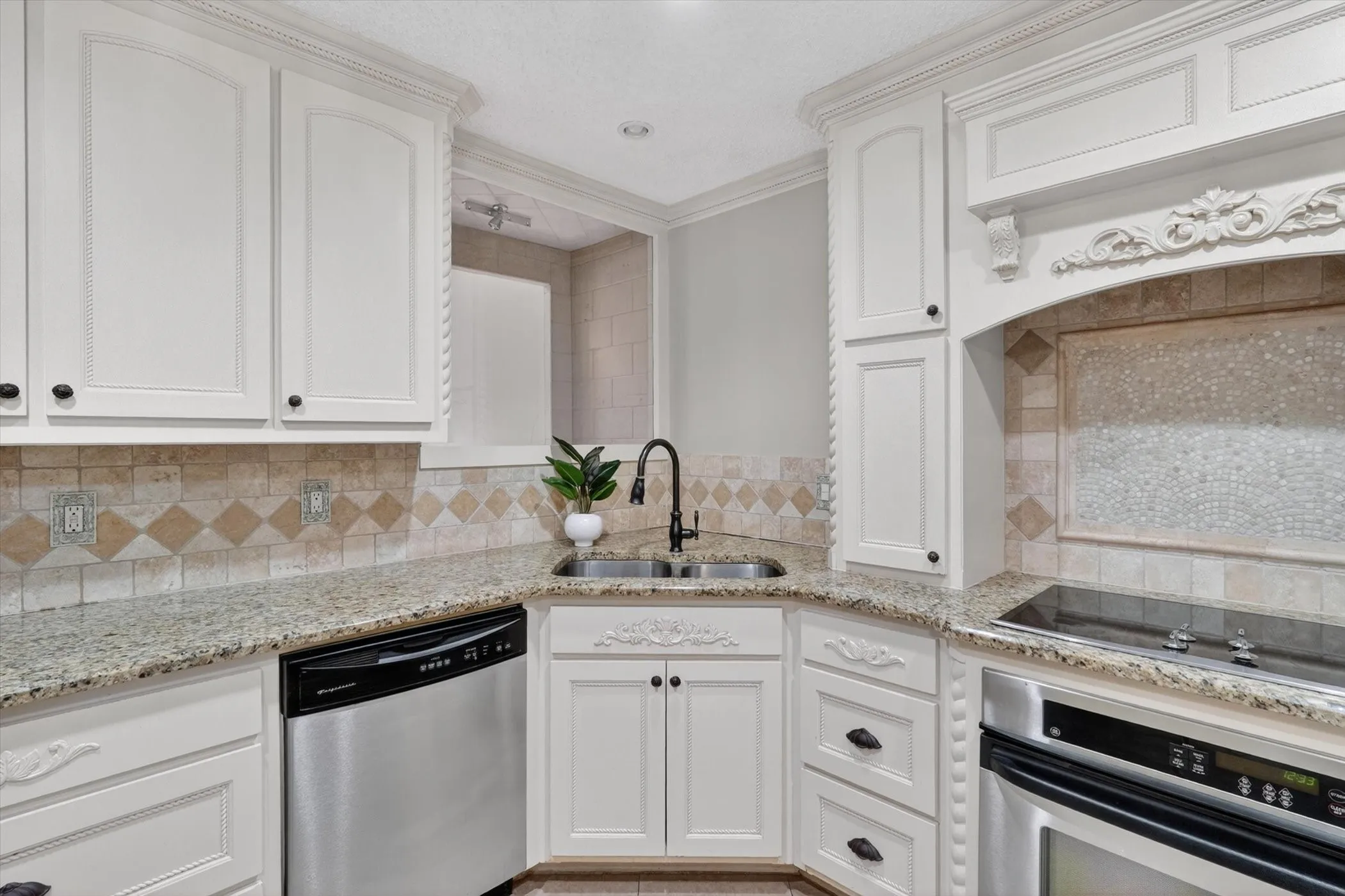 Kitchen featuring white cabinetry with decorative molding, a stainless steel dishwasher, and a stainless steel oven