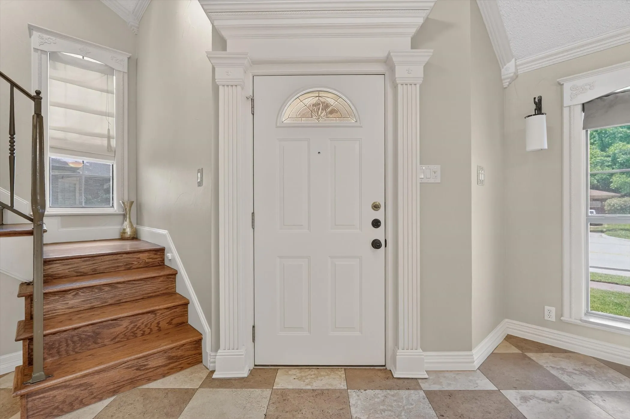 Entryway featuring a decorative front door with an arched glass insert, flanked by fluted pilasters