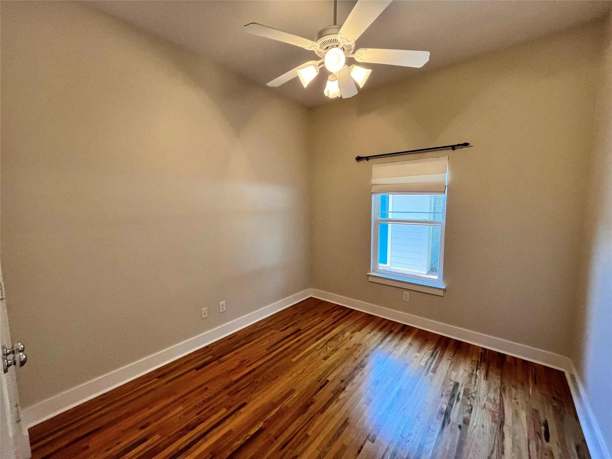 Second bedroom with a ceiling fan and large window.