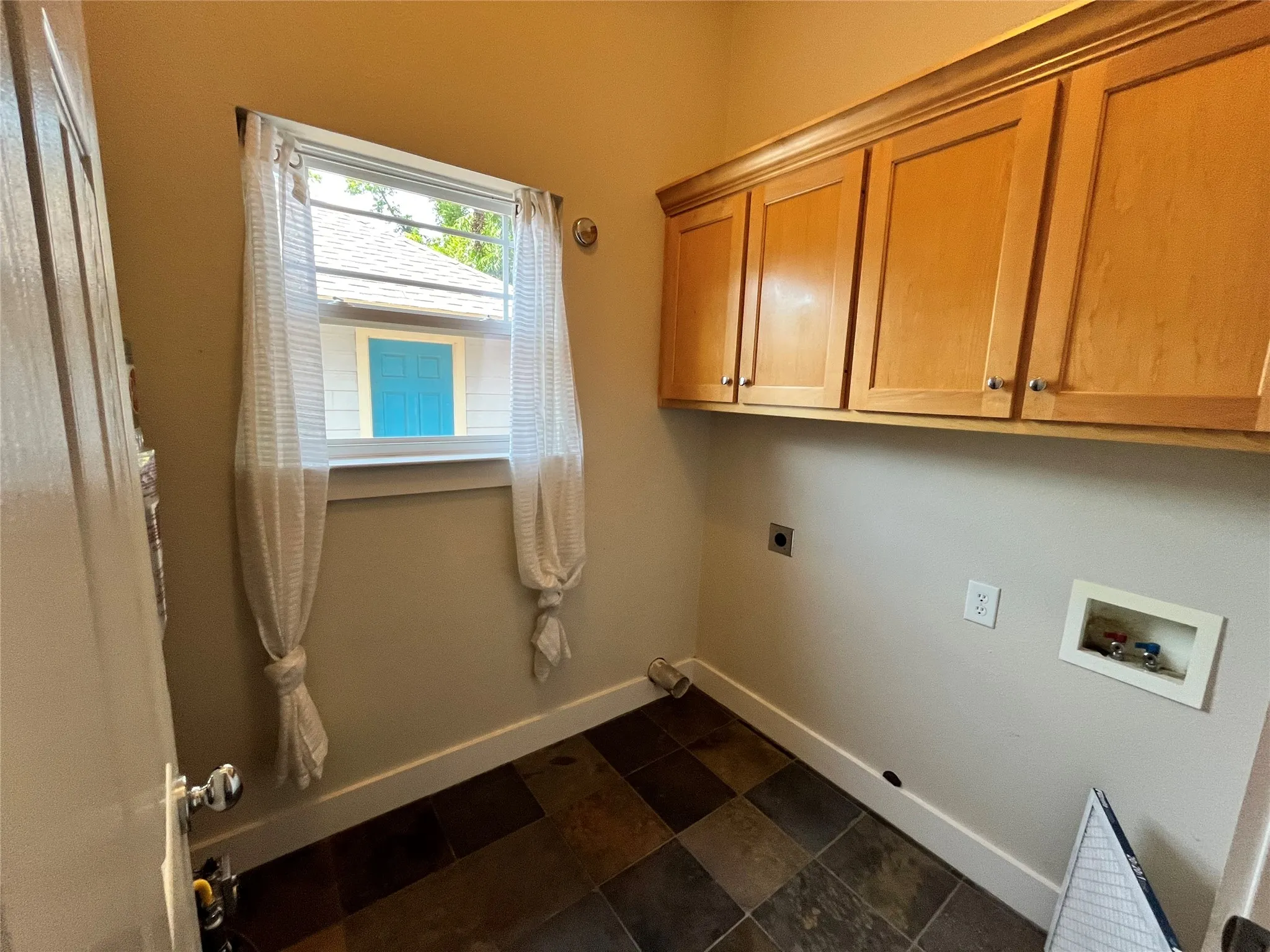 Convenient laundry room with extra storage cabinets and a window.