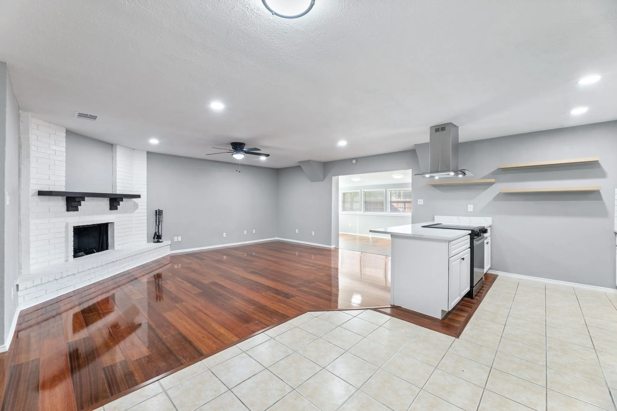 Kitchen with new cabinets, appliances & vent a hood, a ceiling fan, open floor plan, and a fireplace