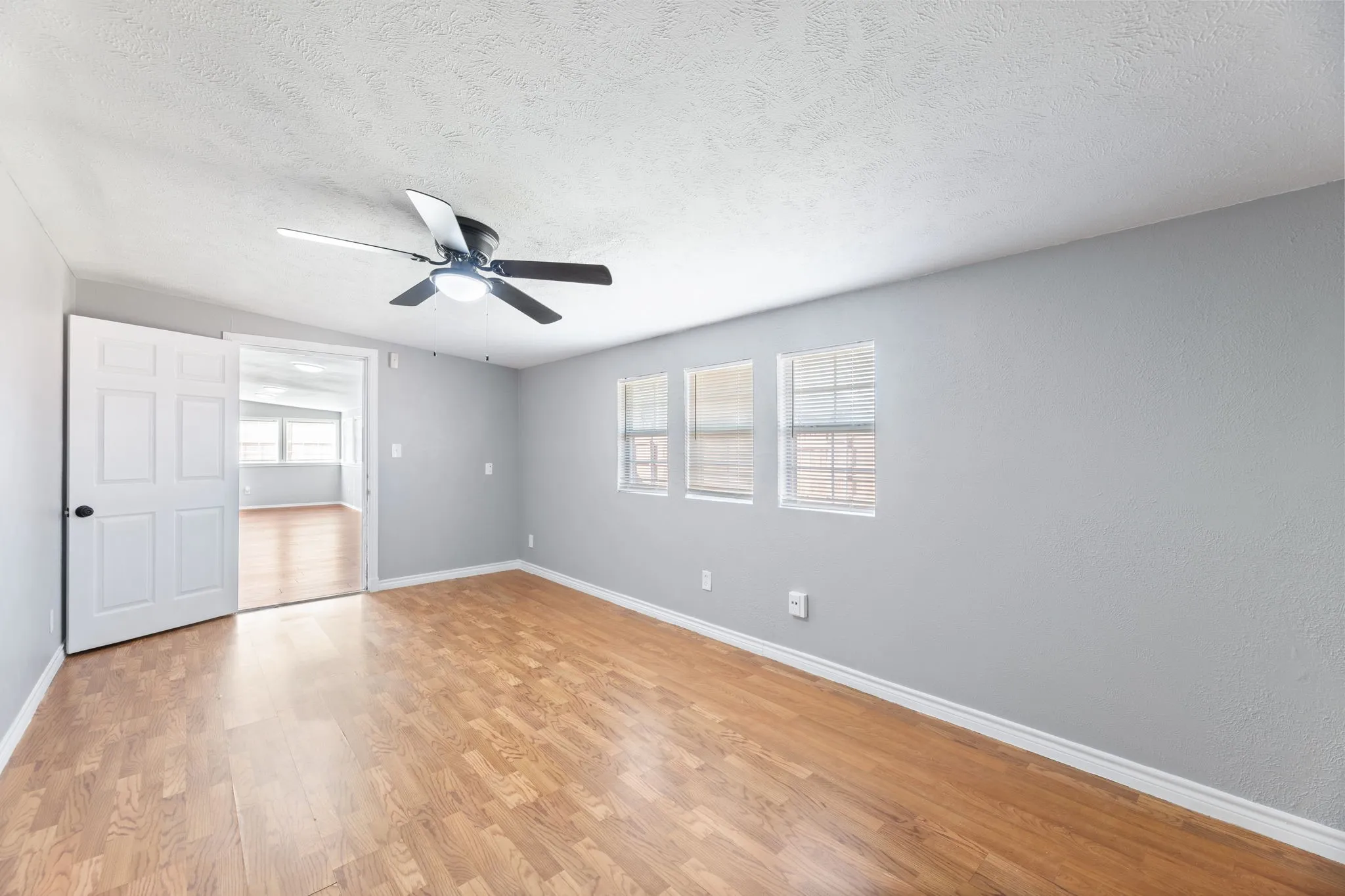 PRIMARY OFFICE, OR PRIVATE LIVING, SITTING AREA. Light wood-type flooring, a textured ceiling, and a ceiling fan
