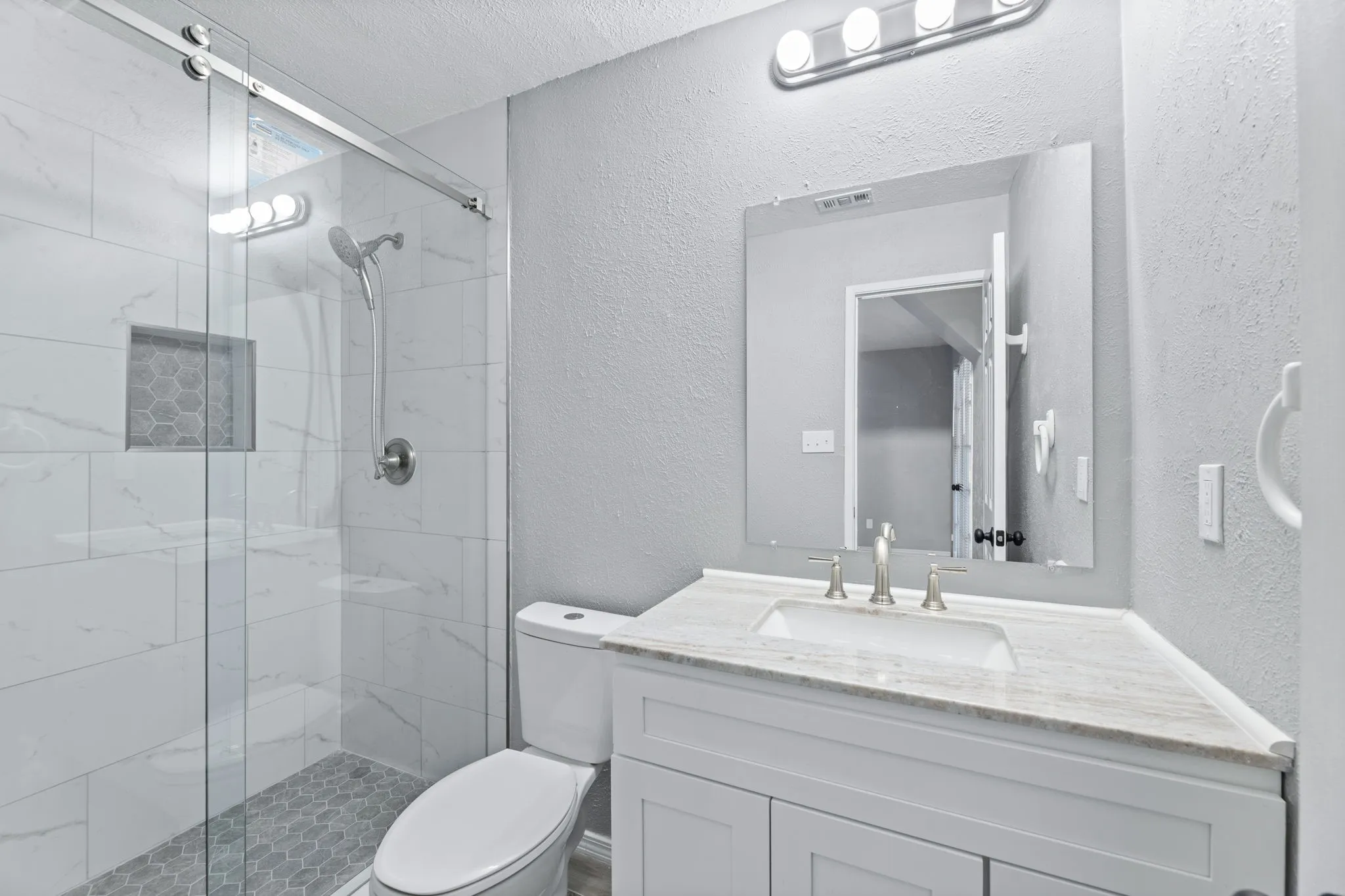 Primary Full bath featuring a textured wall, a marble finish shower, vanity, and a textured ceiling