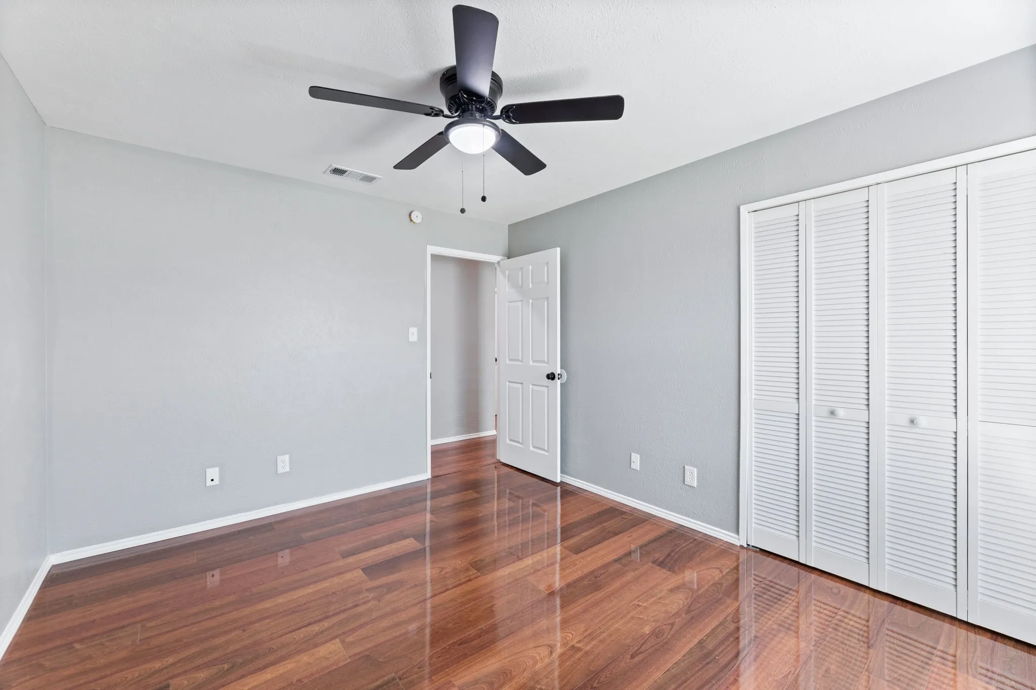 3rd bedroom featuring dark wood-style flooring, a ceiling fan, and a closet