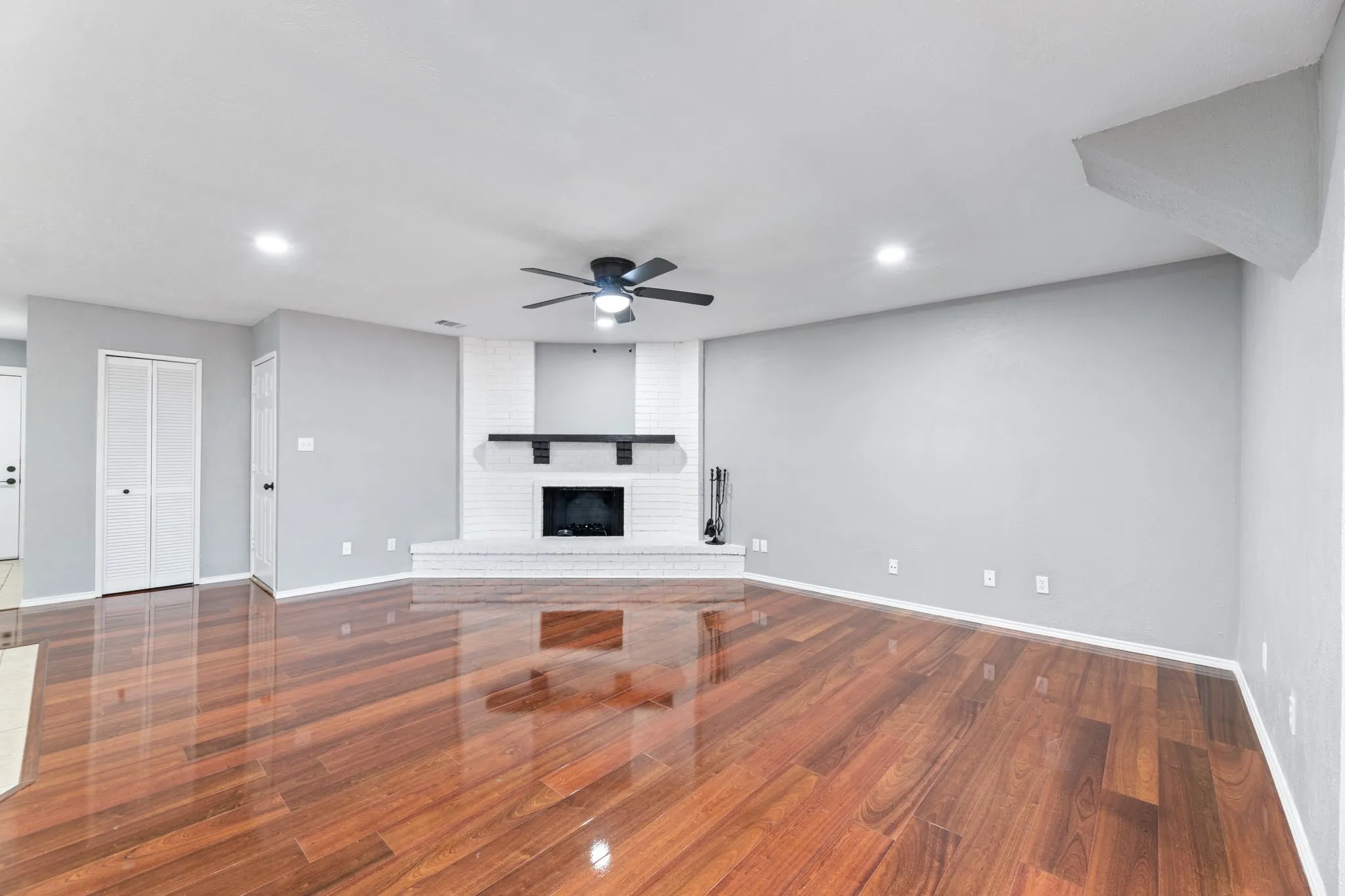 Unfurnished living room with a fireplace, ceiling fan, wood finished floors, and recessed lighting