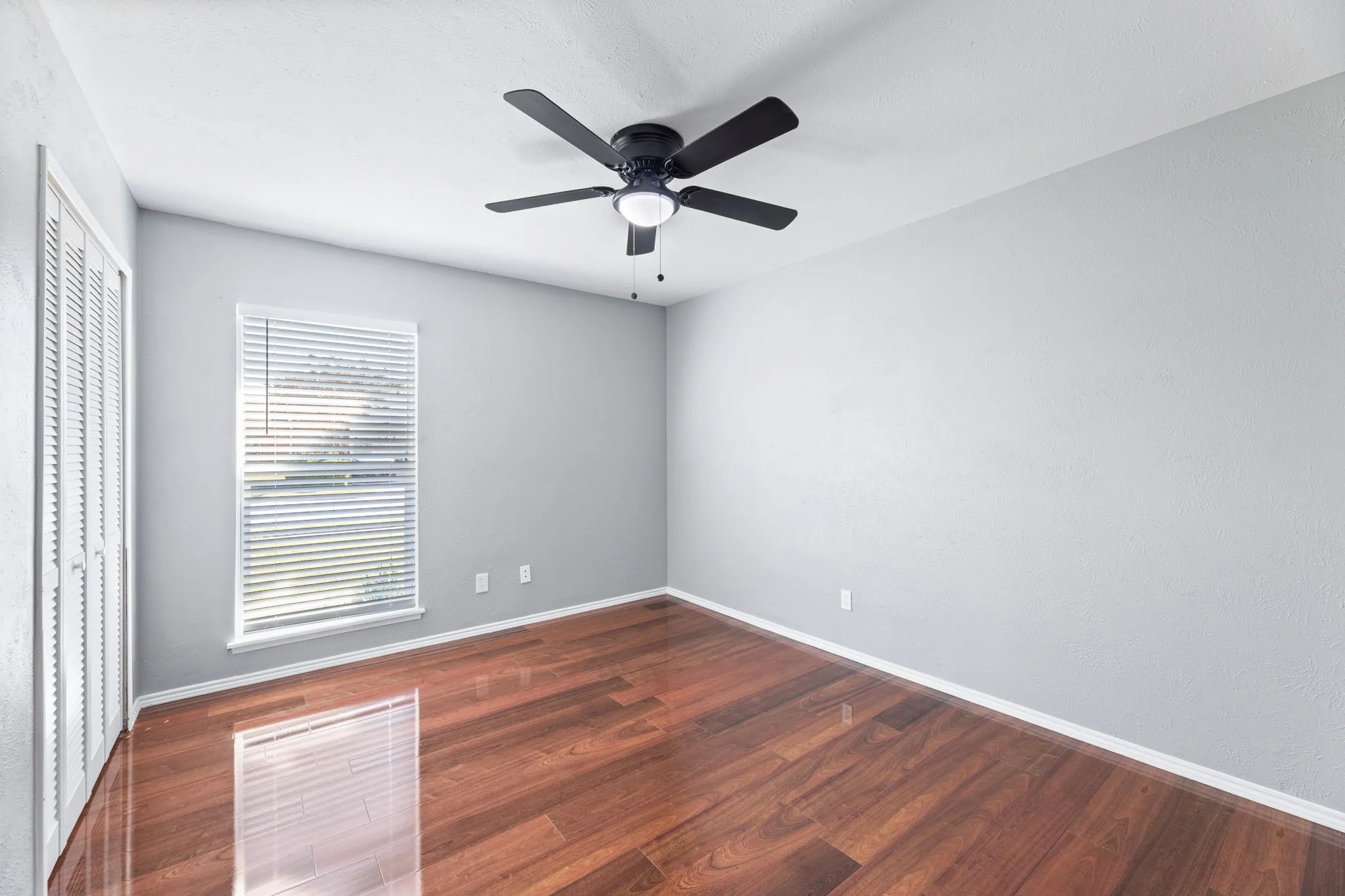 Another view of 3rd bedroom with dark wood finished floors, ceiling fan, and a closet