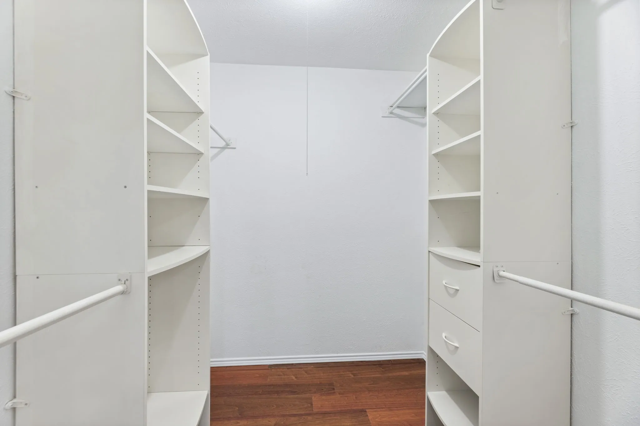 PRIMARY Walk in closet with dark wood-type flooring