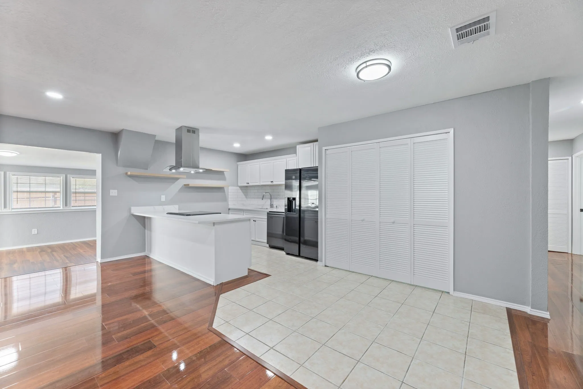 Kitchen with light wood finished floors, white cabinets, a peninsula, tasteful backsplash, and stainless steel appliances